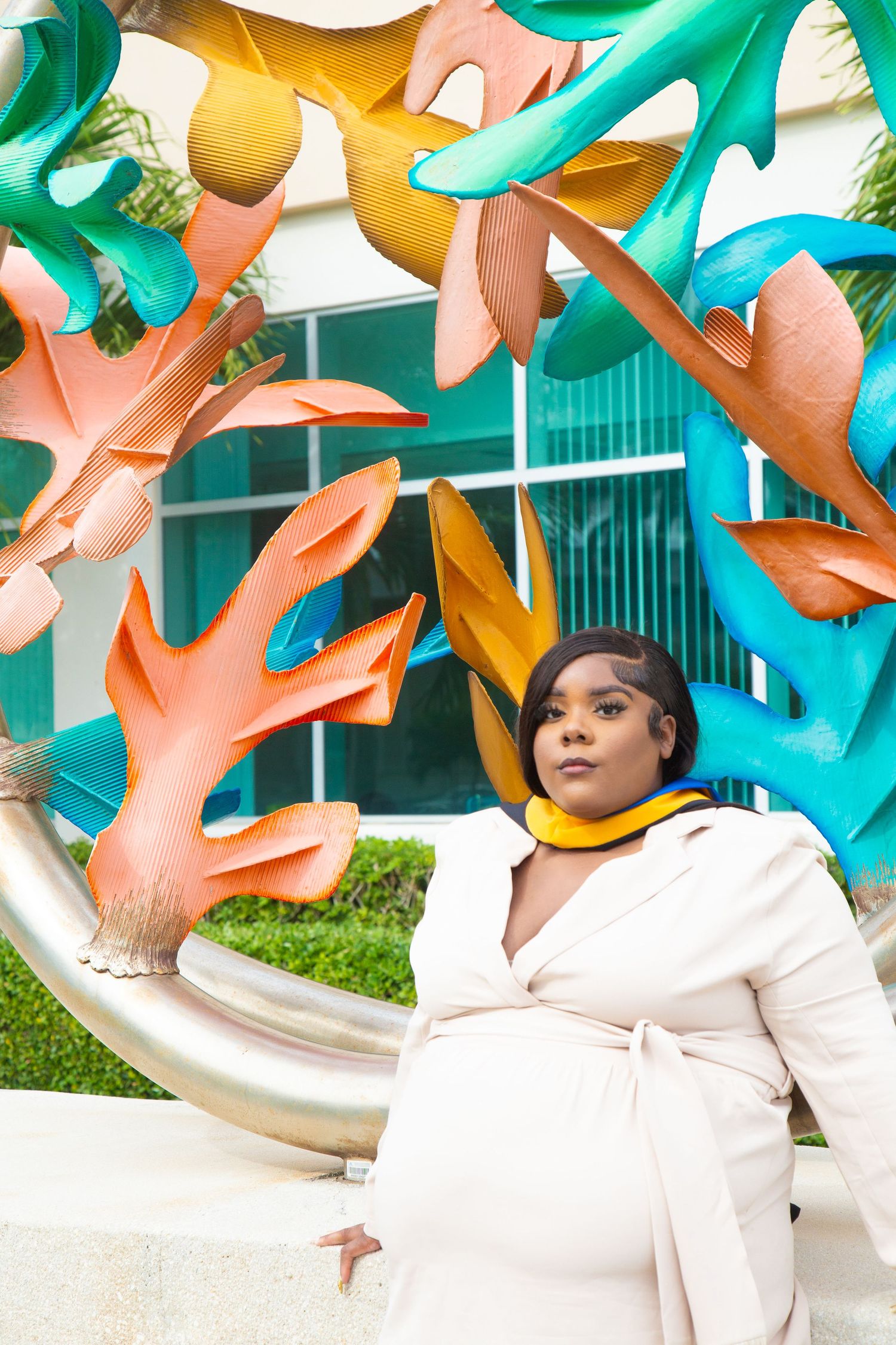 Portrait of graduate in white coat against colorful artistic sculpture installation.