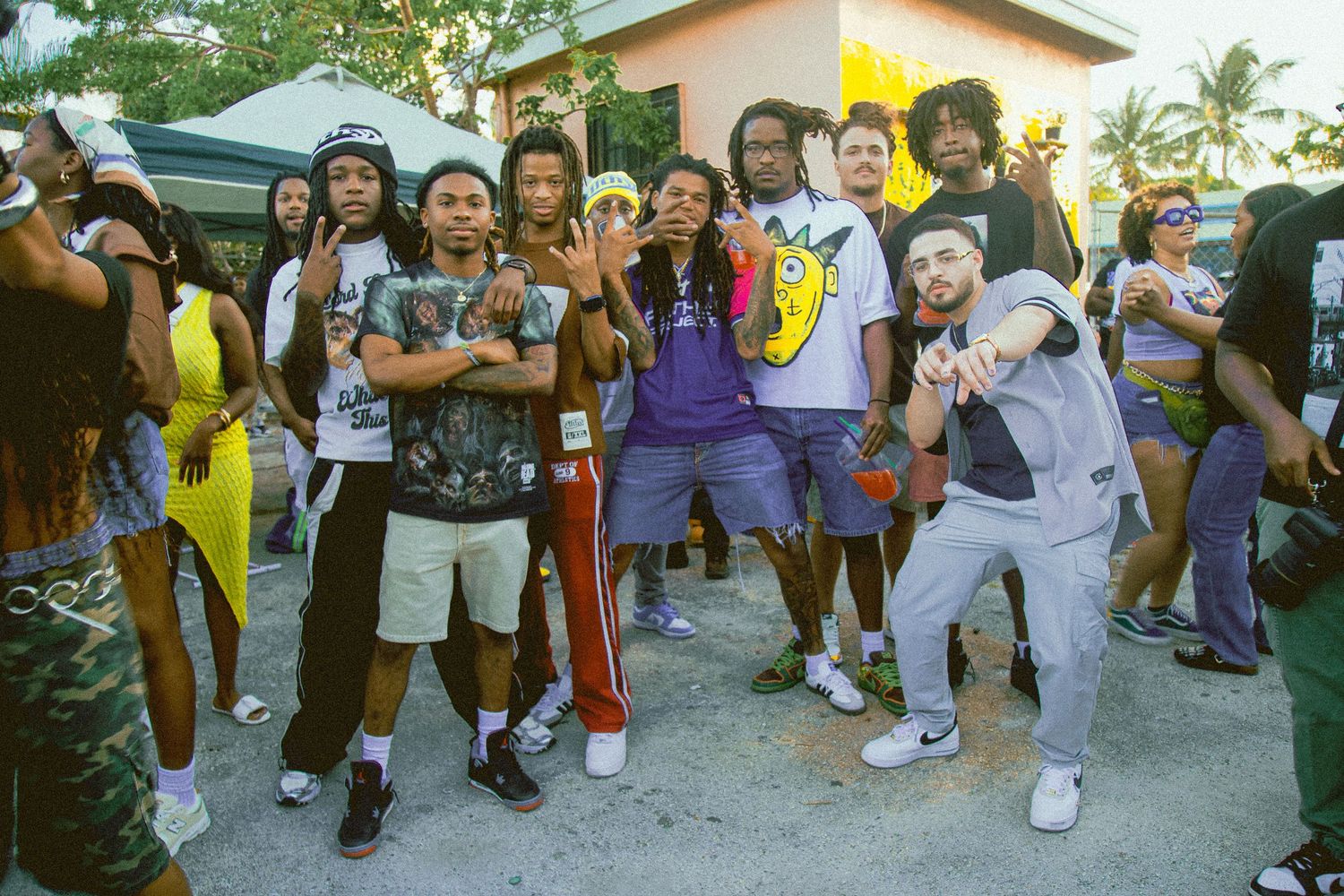 Energetic crowd dancing and posing at an outdoor community gathering.