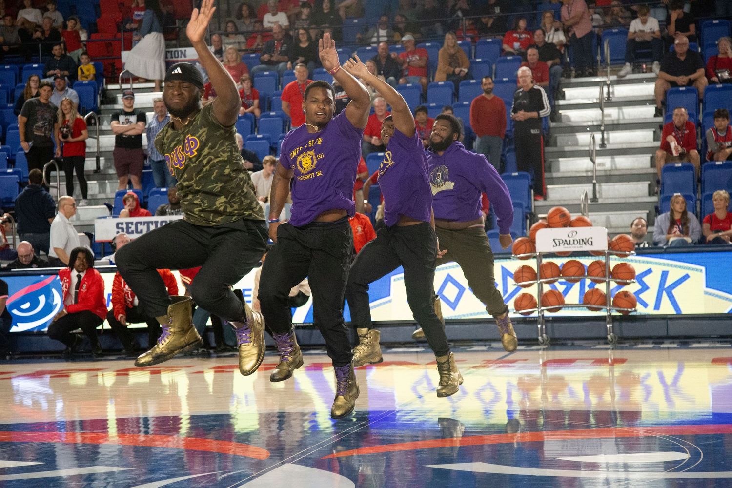 Dance team members executing choreographed moves during basketball game halftime show.