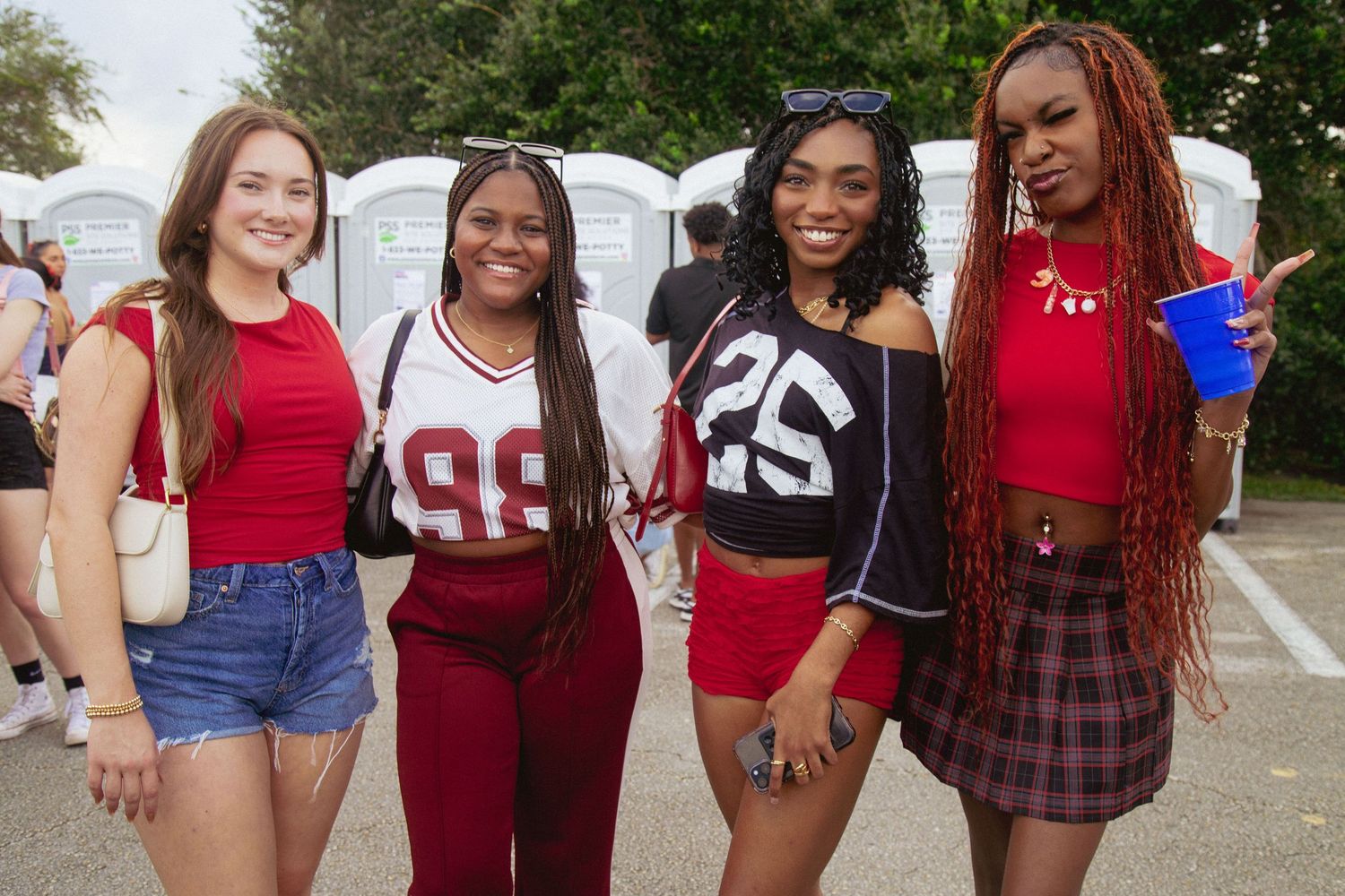 Friends in casual outfits and red tops posed together at outdoor gathering.