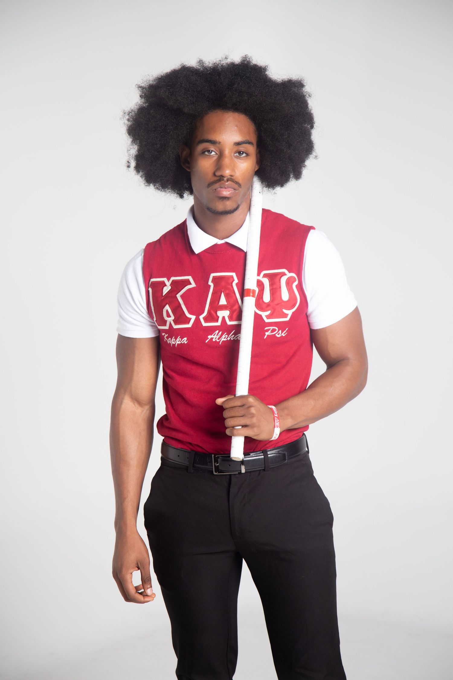 Person in red and white fraternity vest poses confidently against white backdrop.