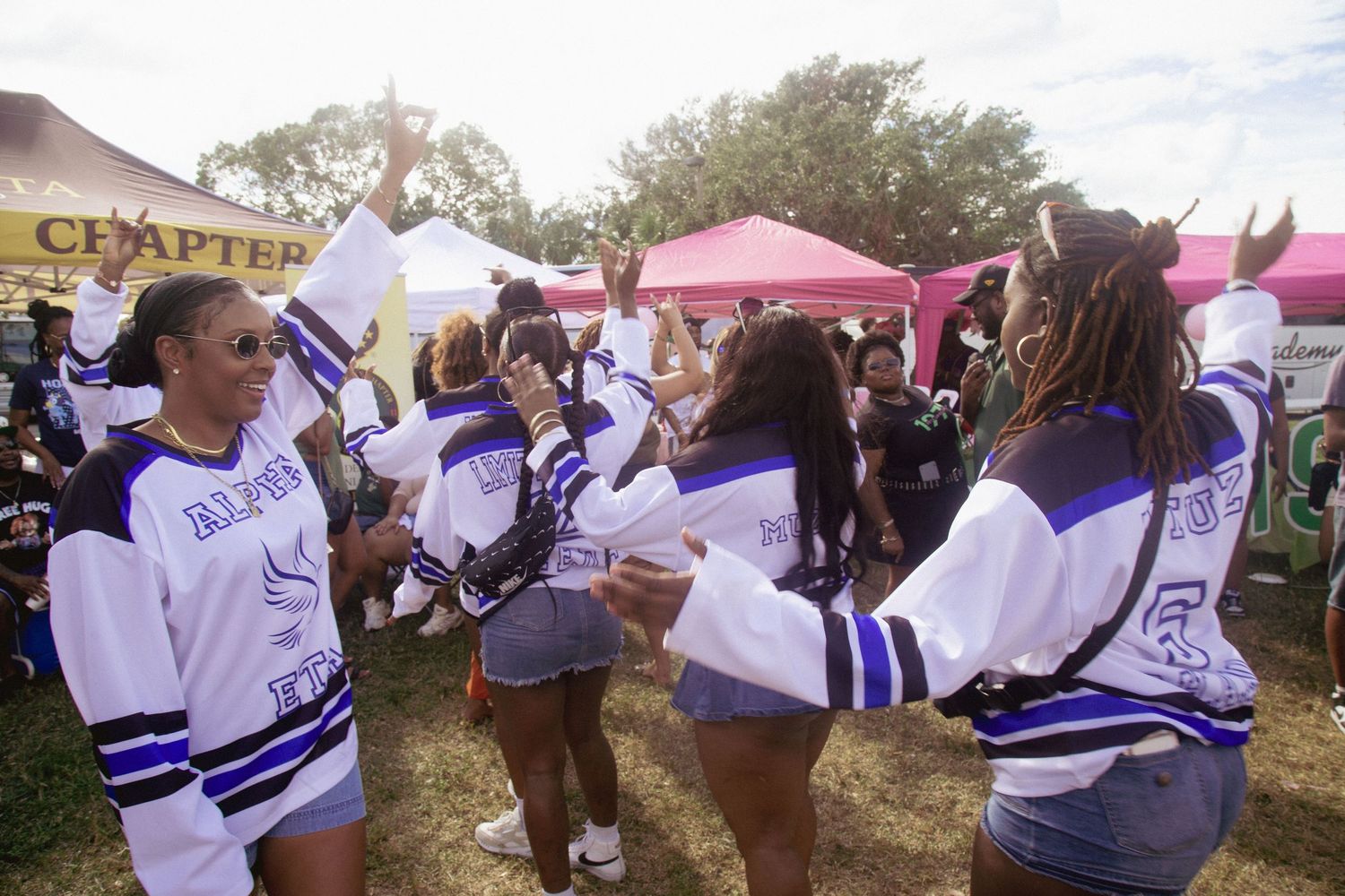 Group wearing matching white and blue jerseys gathered at outdoor event.