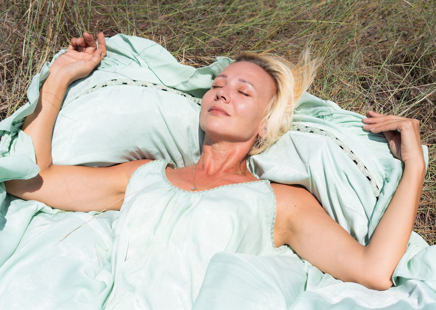 Woman in mint green dress lying down outdoors.