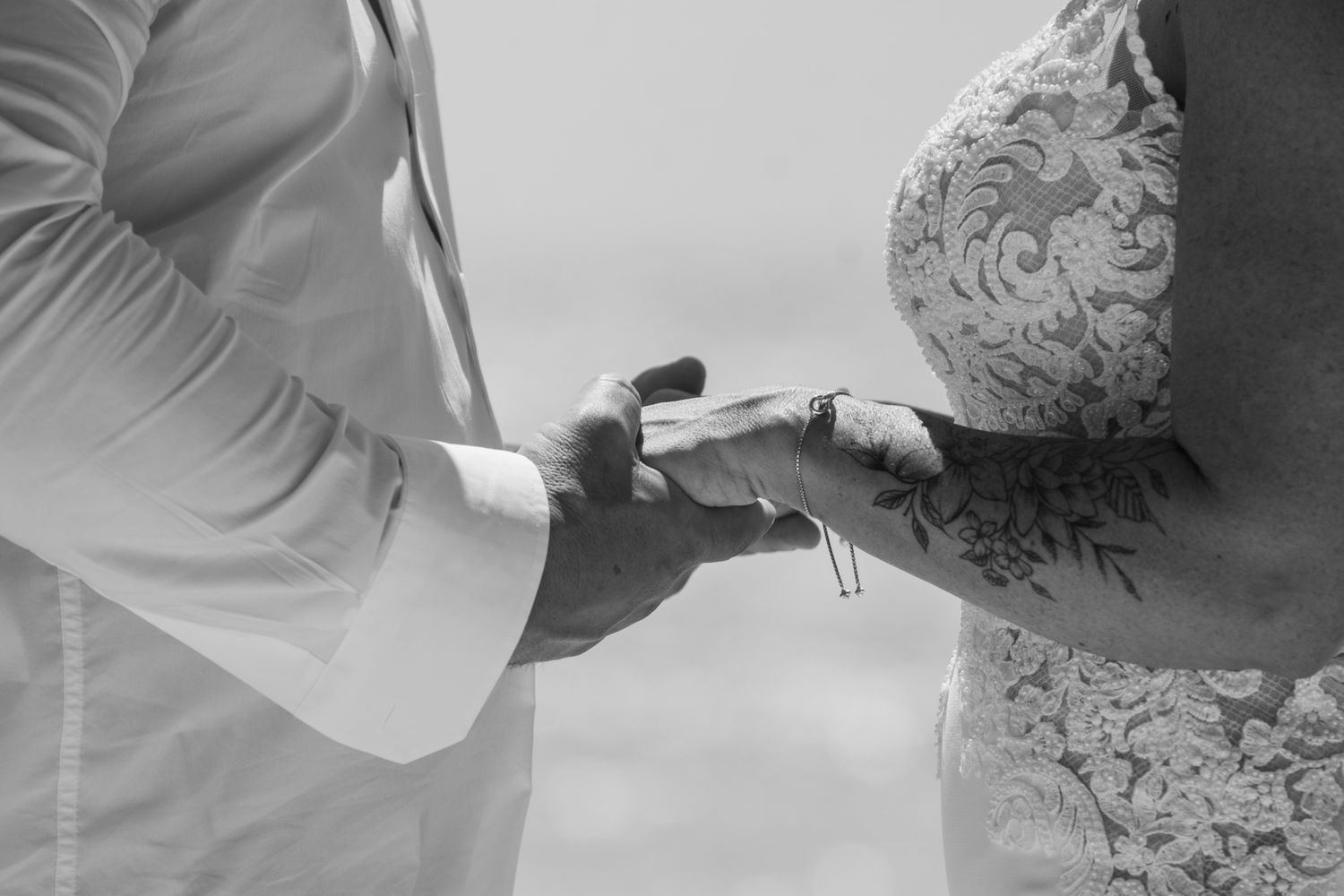 A black and white close-up shot of hands exchanging rings during a wedding ceremony.