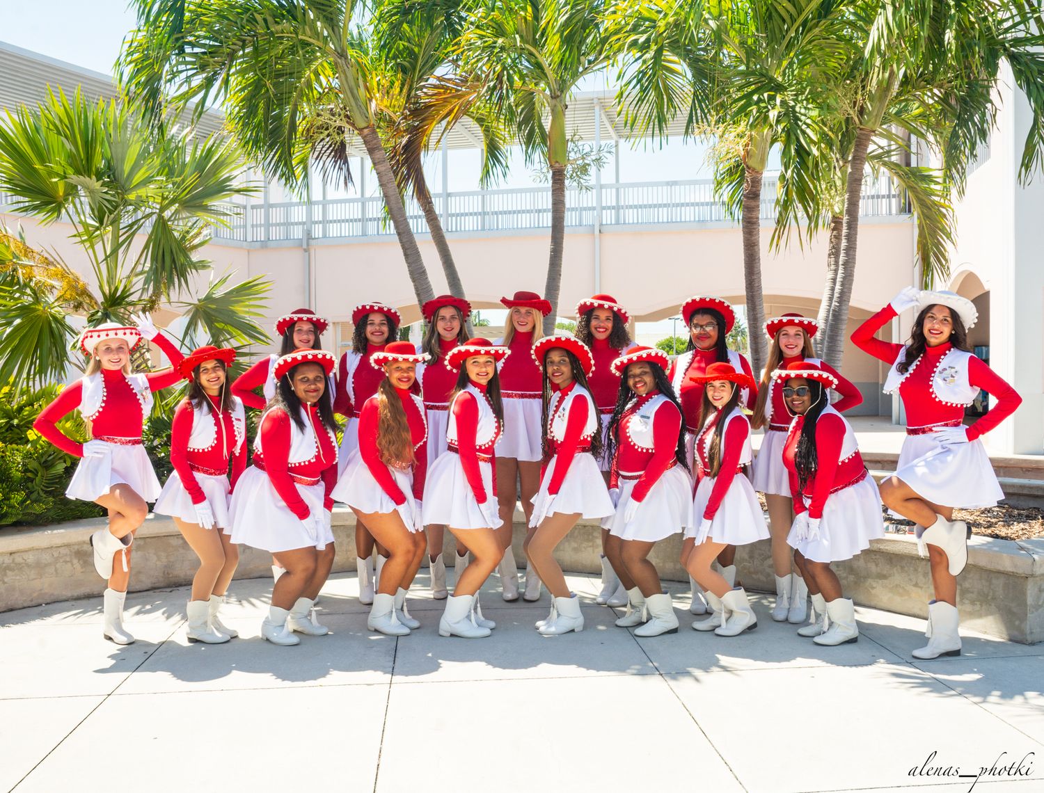 Group photo of a sorority in matching red and white outfits posing together under palm trees.