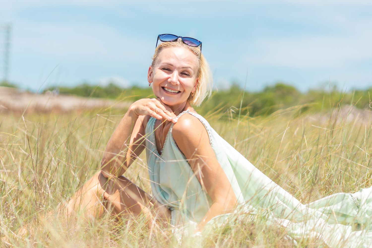 A summery portrait of someone relaxing in a sun-drenched field of tall grass.