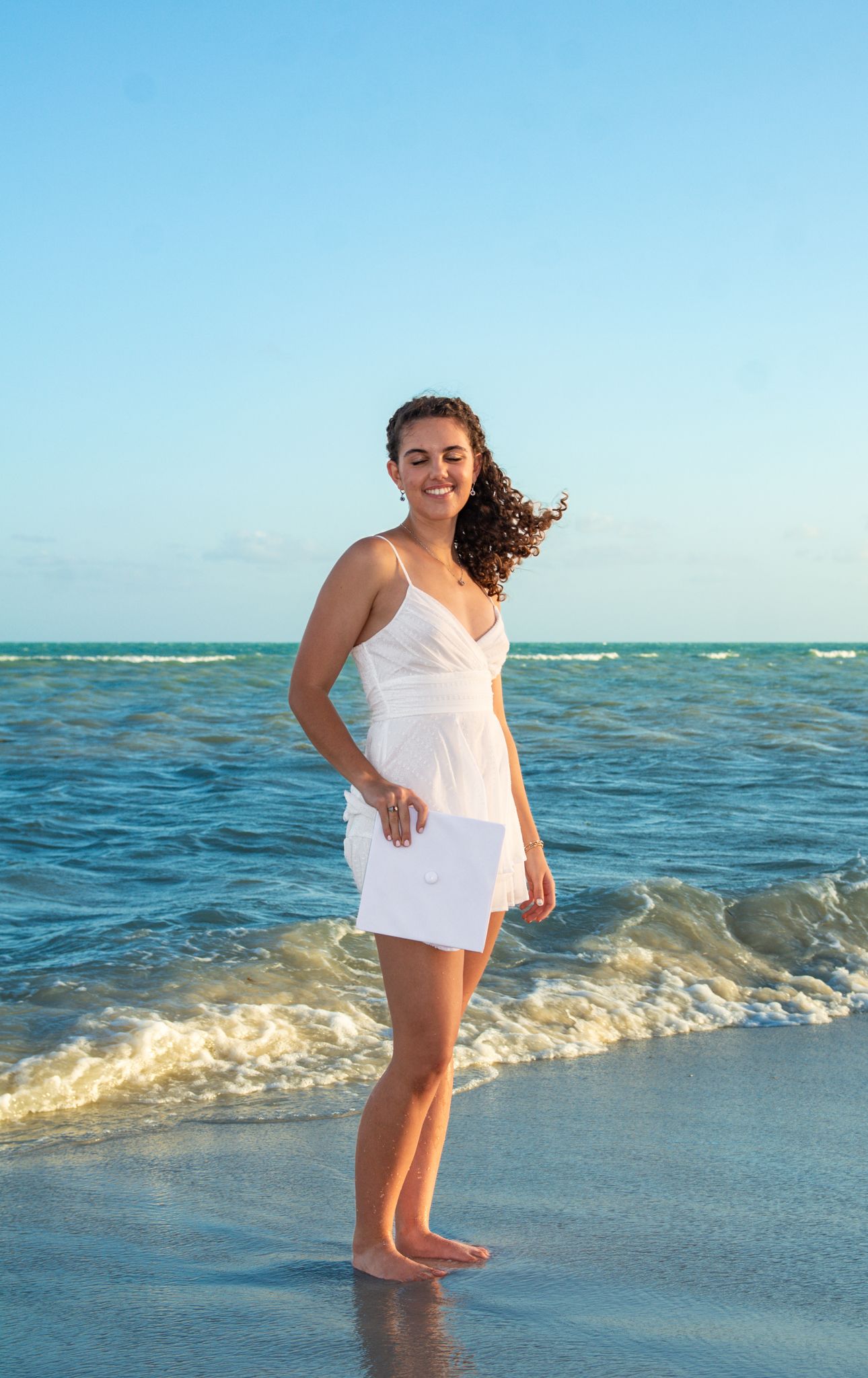 White sundress silhouette against turquoise ocean waves on tropical beach.
