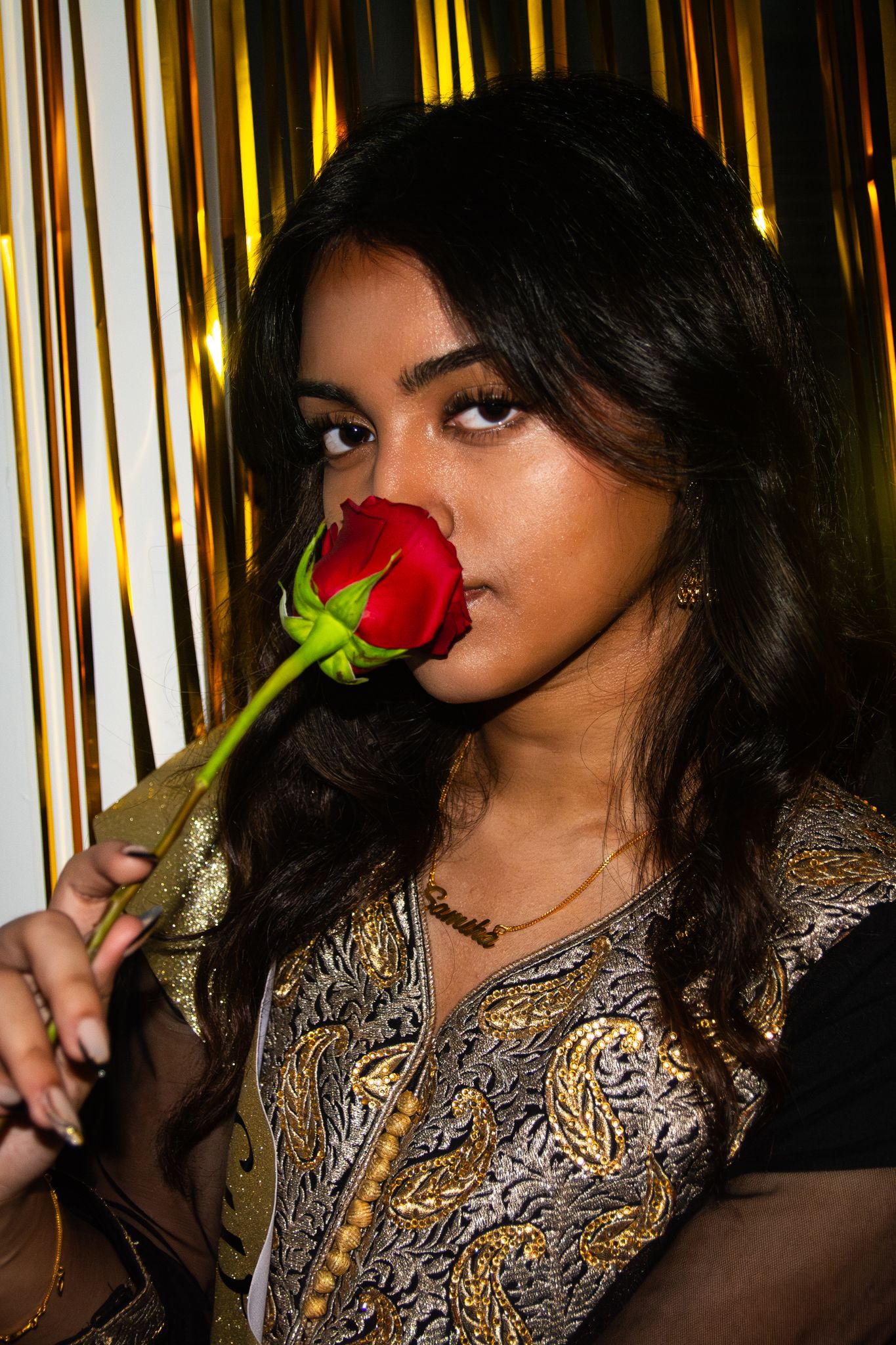 Artistic portrait with red rose against gold metallic backdrop.