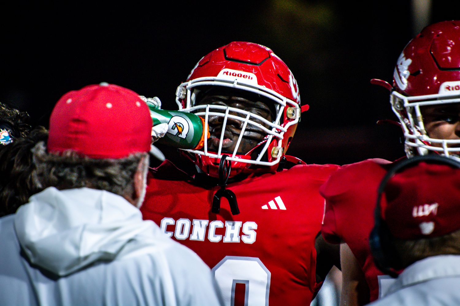 Football players in red uniforms line up in defensive formation during a night game.