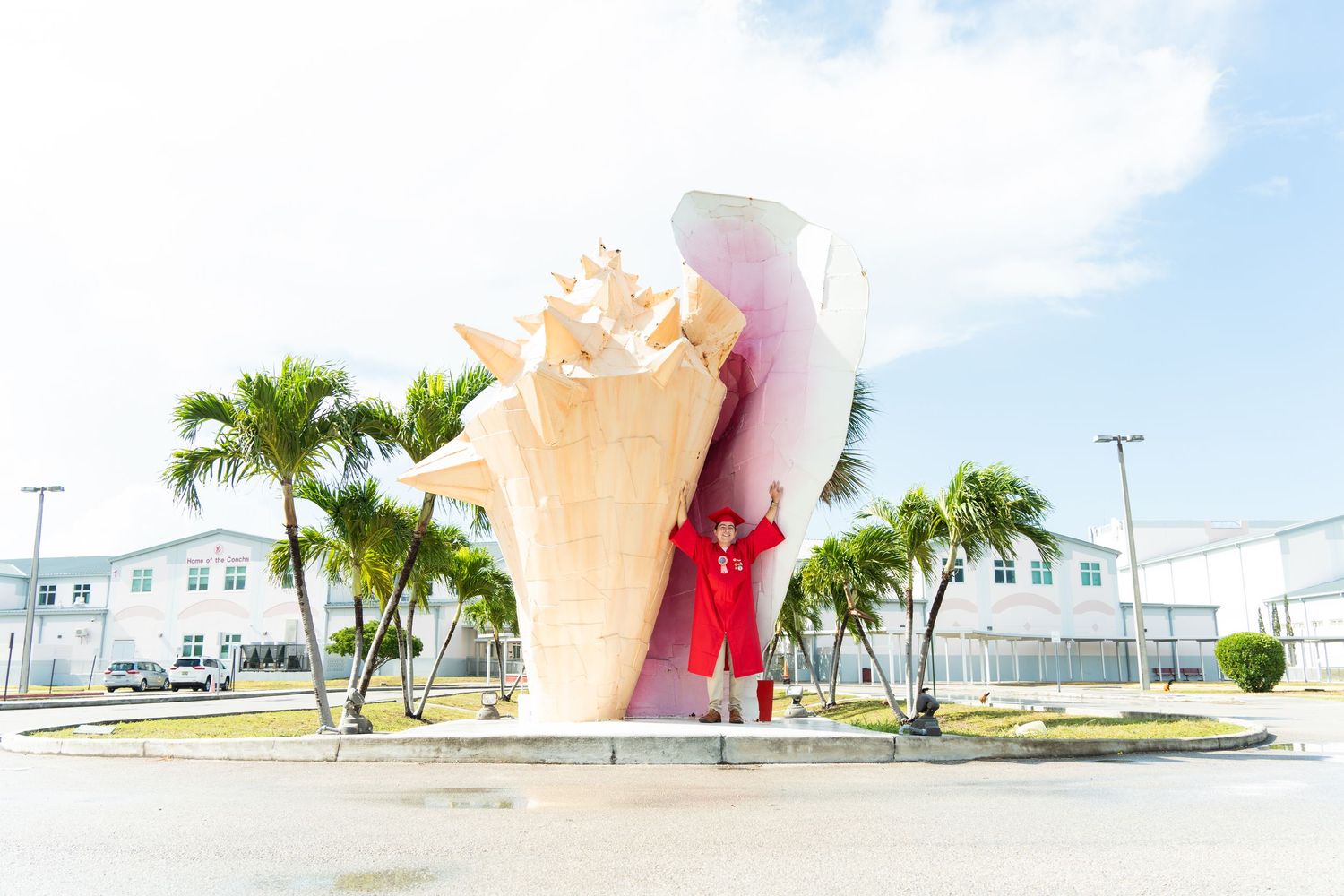 Person in red gown poses before a giant conch shell sculpture roundabout in the Turks and Caicos Islands.