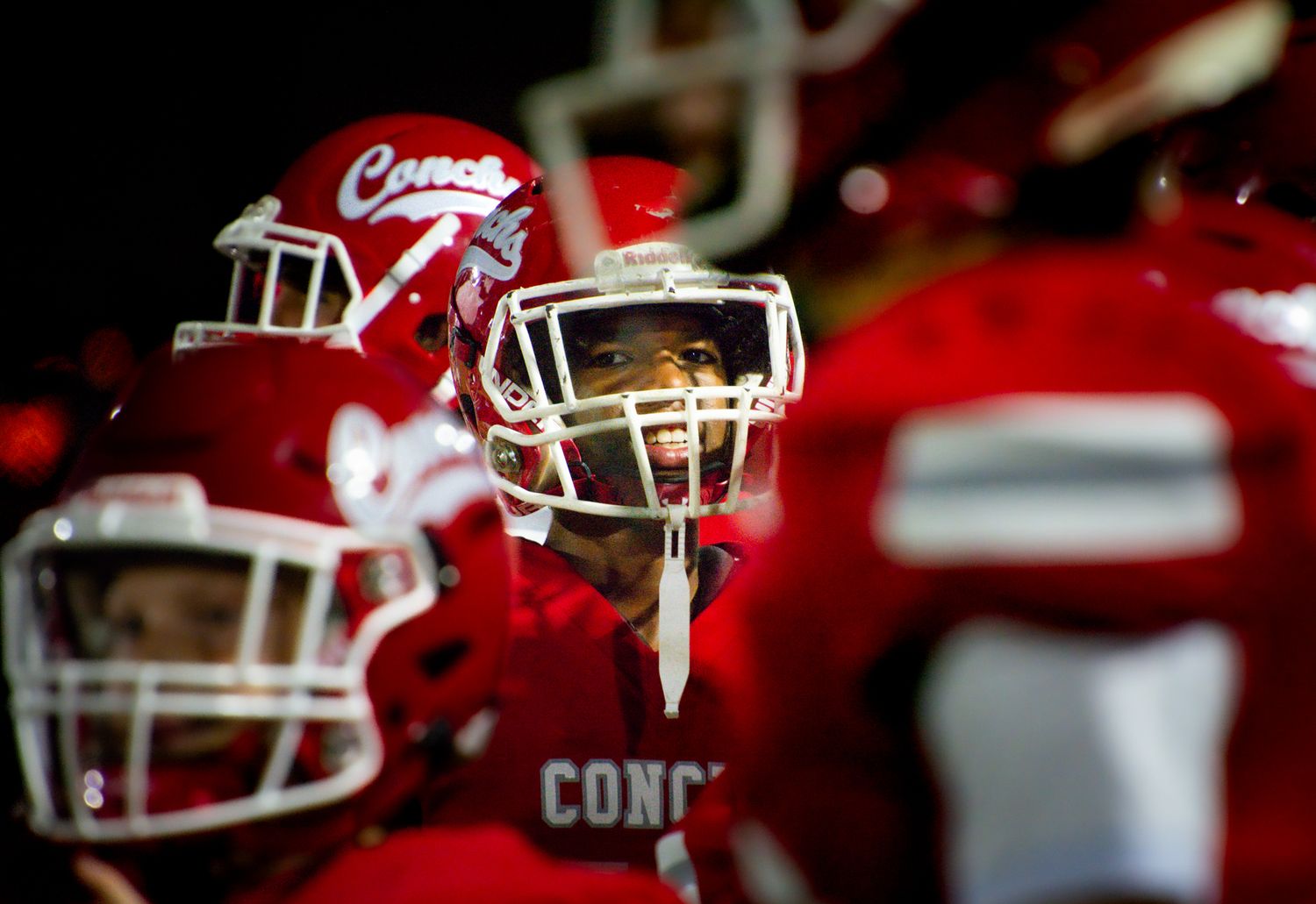 Football player in red helmet and uniform focused during game.
