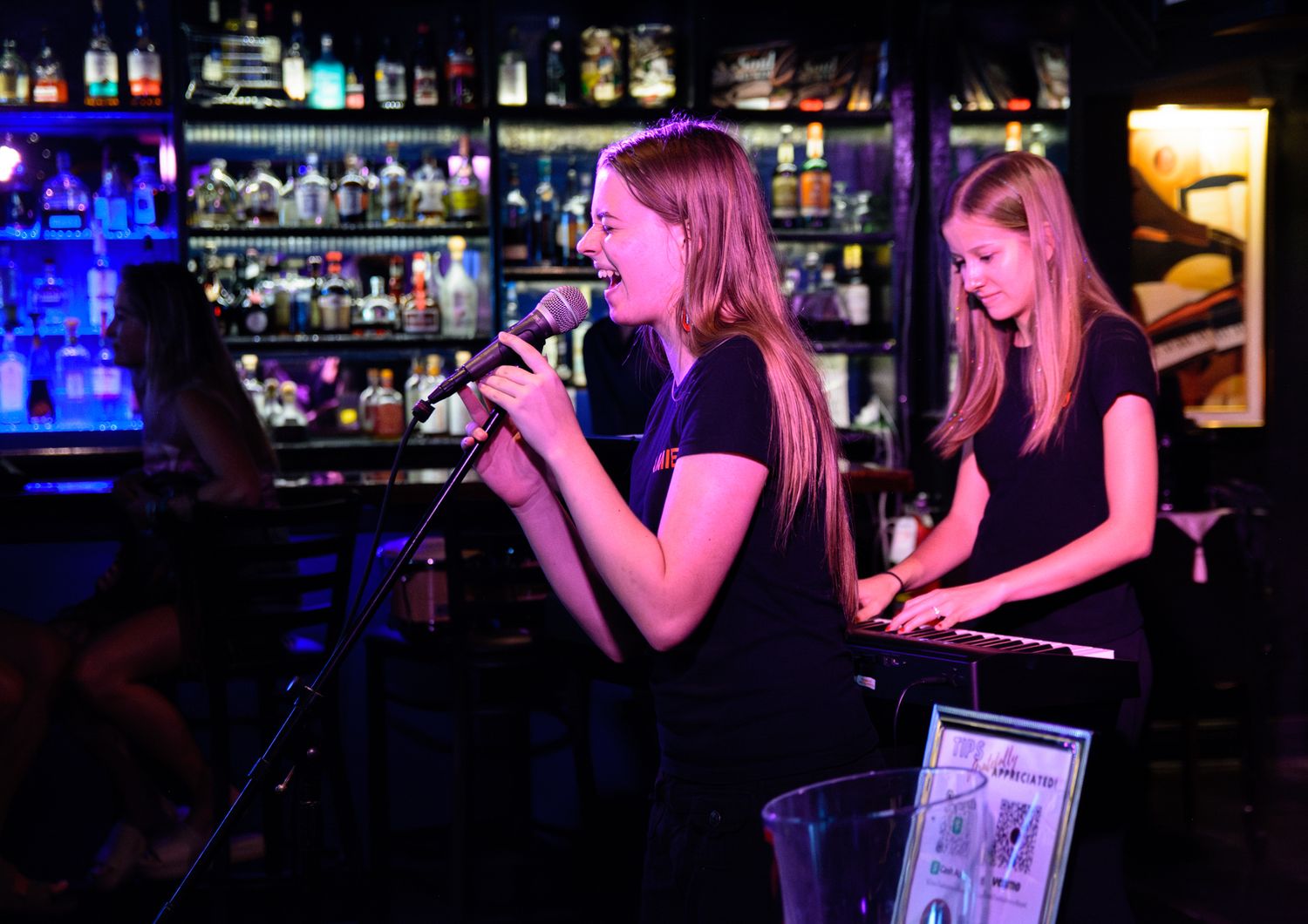 Two performers entertain at a bar venue with microphone and keyboard.