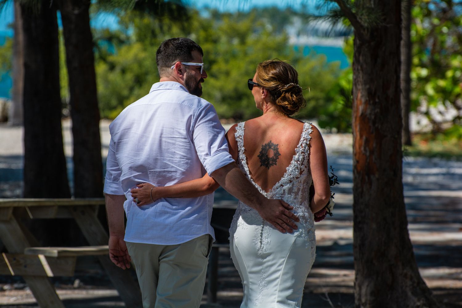 A couple walking together on a beach path with palm trees and ocean views.