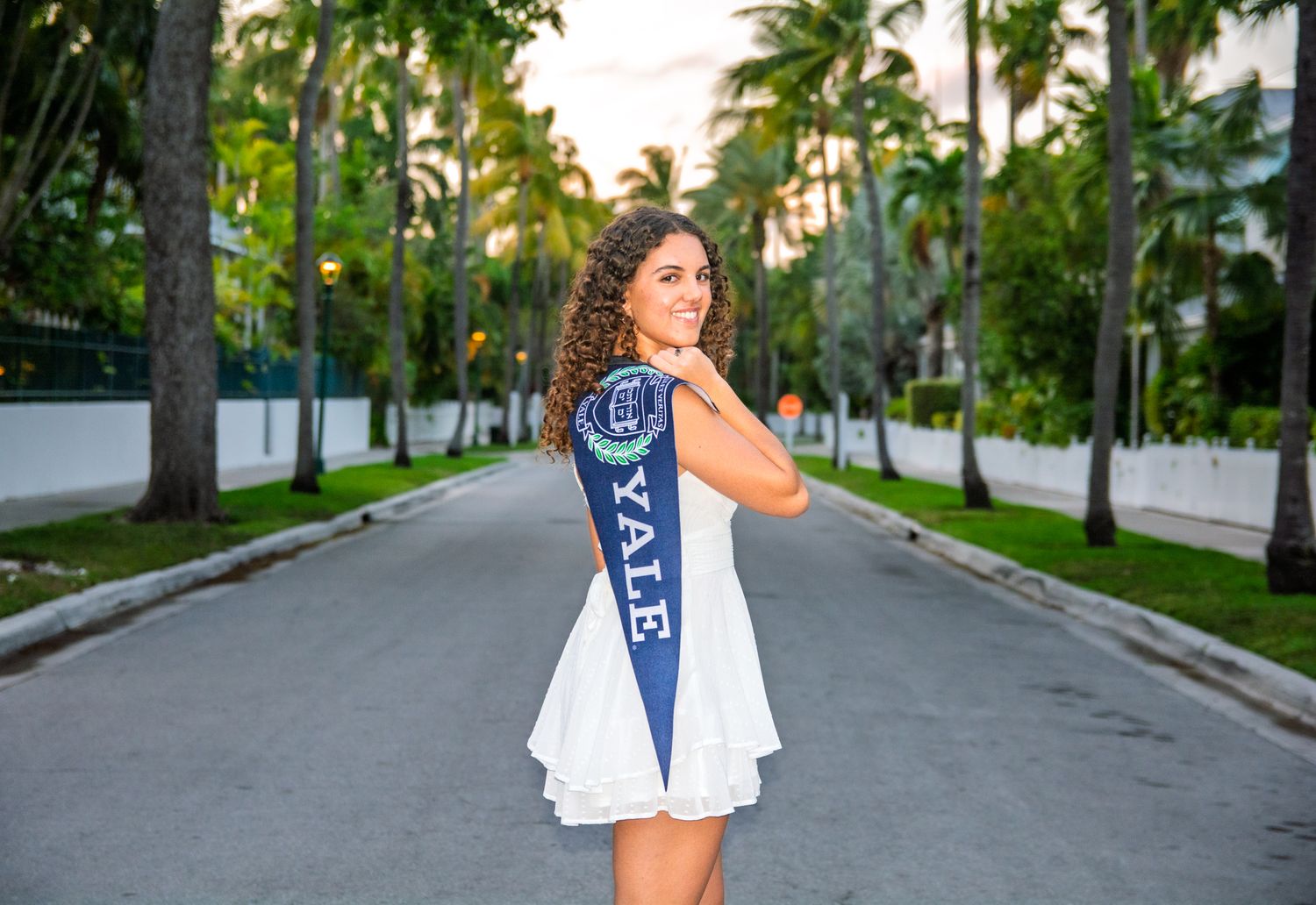 A white tennis dress photographed on a palm tree-lined street.