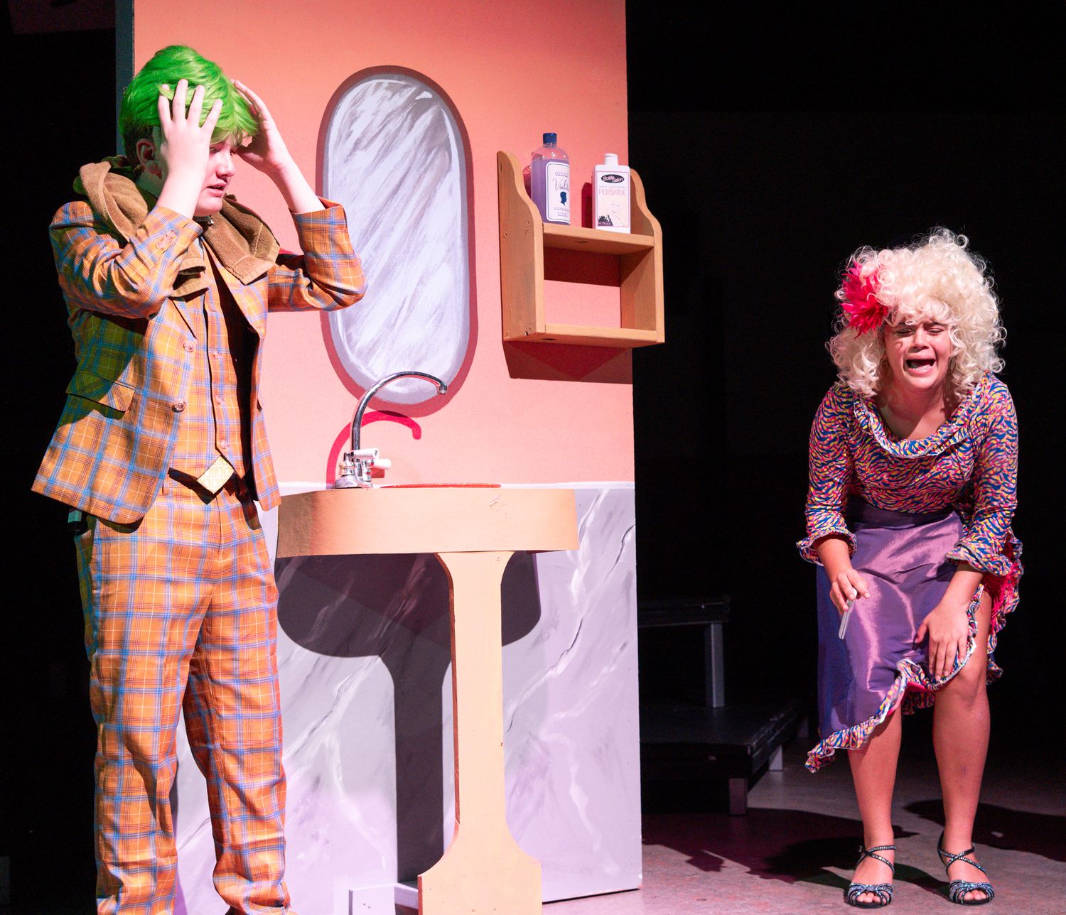 Stage performance scene with actors in colorful outfits against pink lighting.