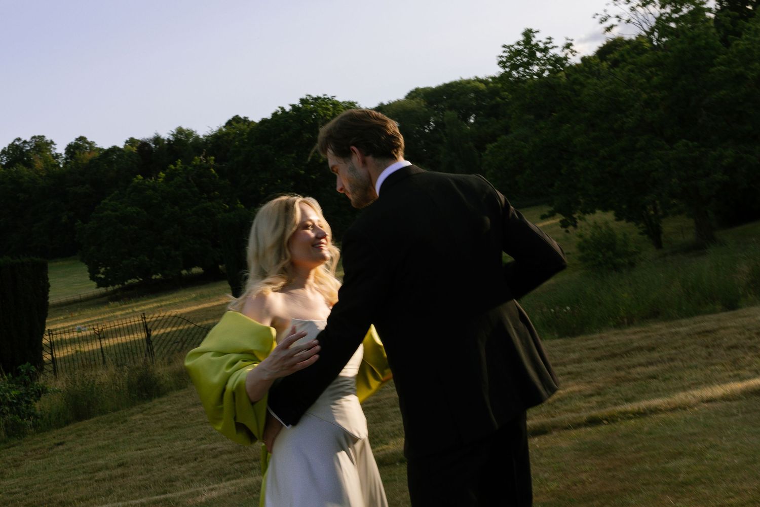 Multiple close up video captures show a couple embracing and dancing in golden sunlight on a grassy outdoor setting.