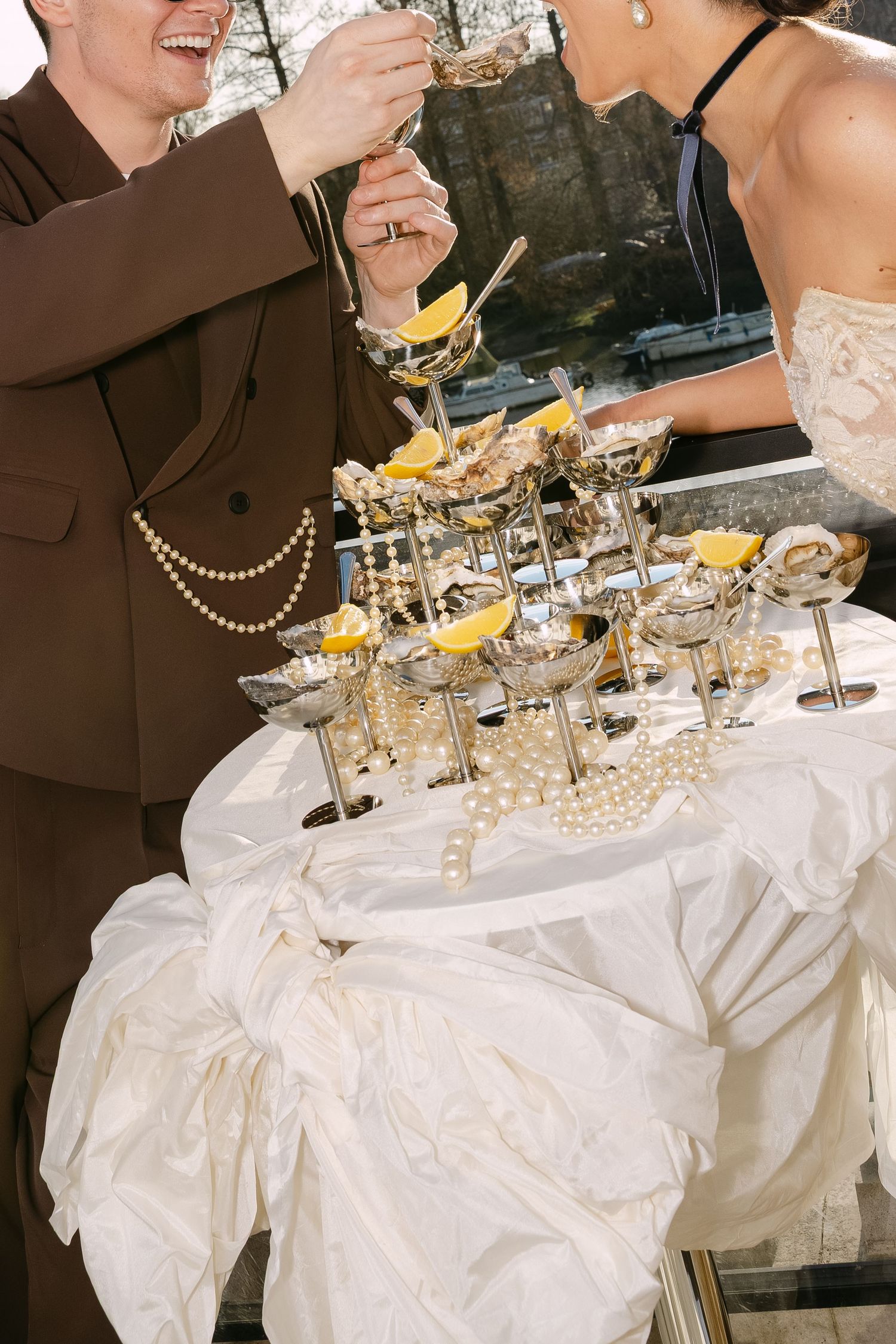 Wedding guests gather around a tower of champagne coupes decorated with pearls and citrus.