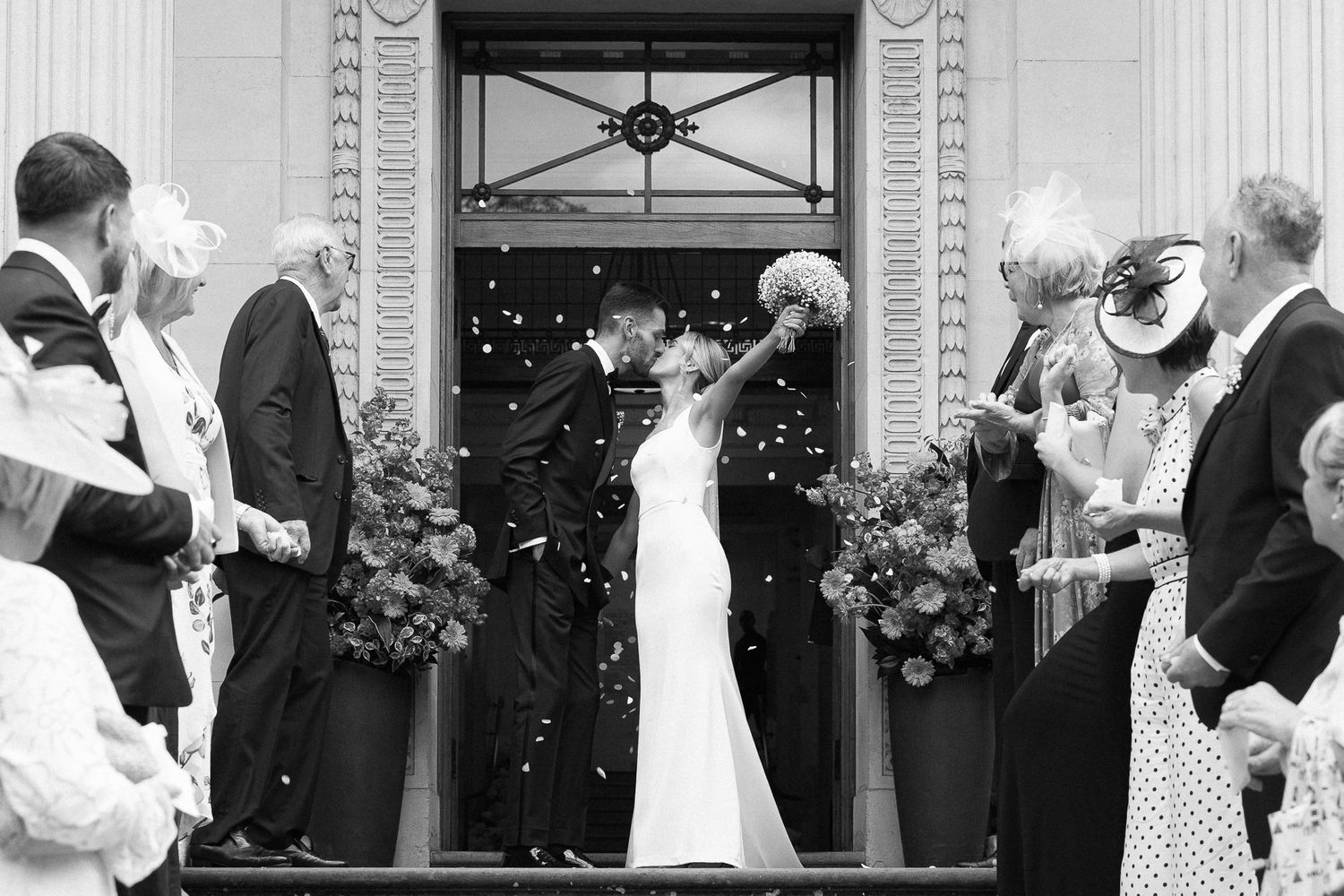 A black and white panoramic photo sequence showing wedding ceremony moments with guests celebrating outdoors.