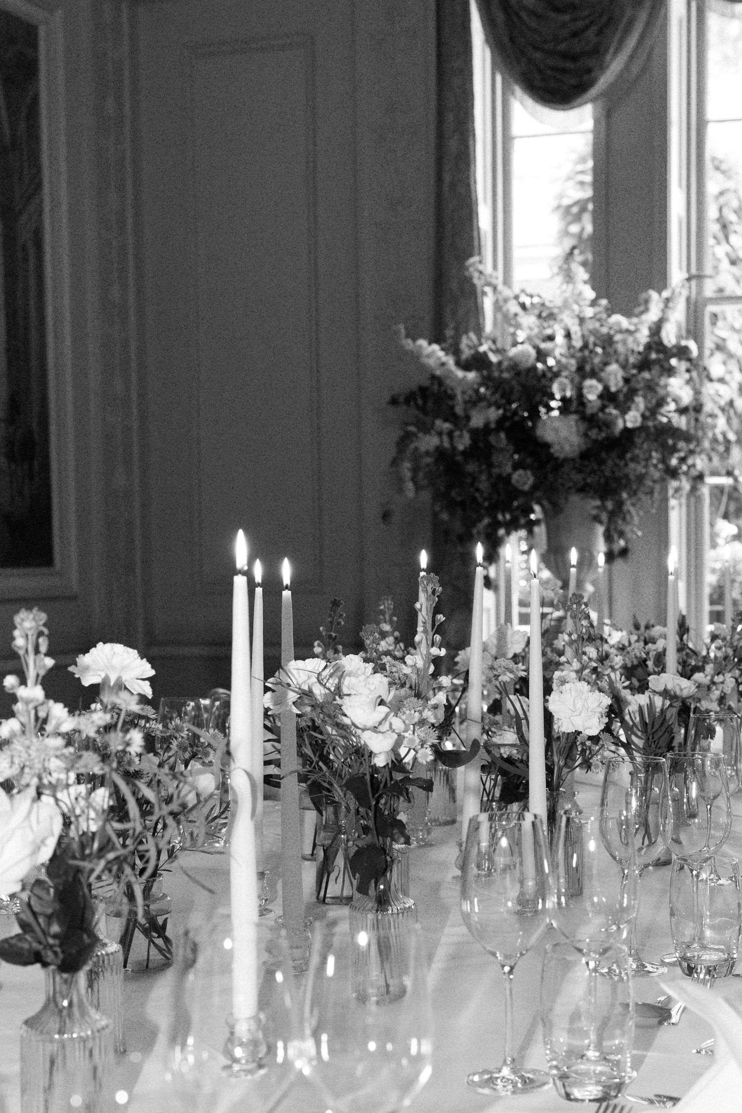 Elegant table setting with crystal vases, white flowers and candlesticks for a formal event.