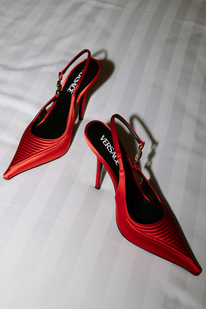 Red patent leather slingback high heel shoes displayed on white bedding from different angles.