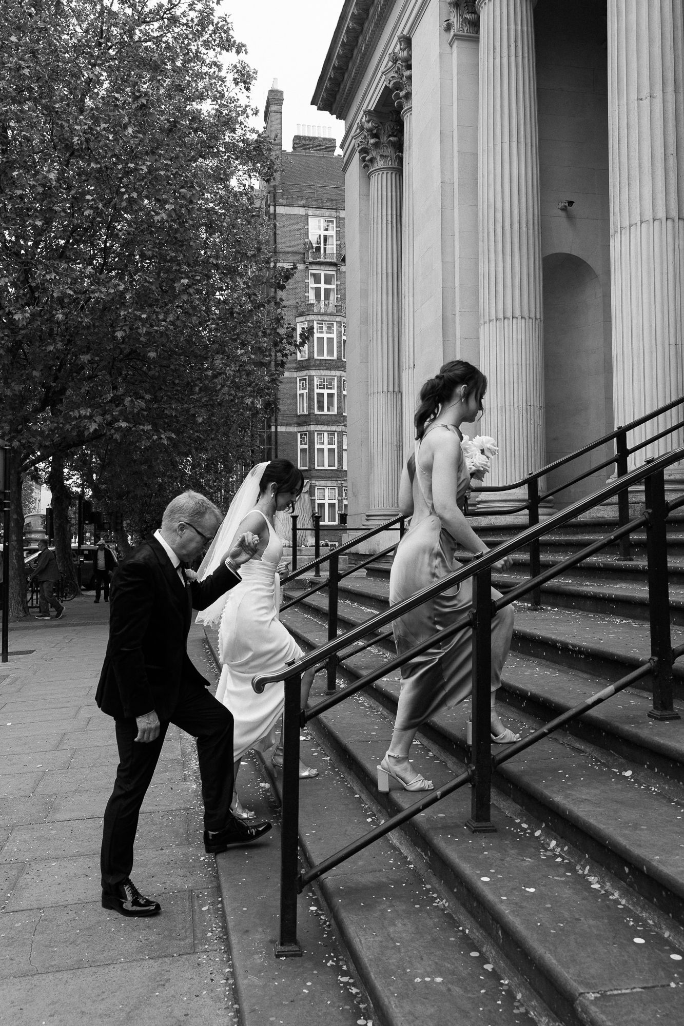 A sequence of black and white photos shows two people playfully climbing up stone steps with columns in the background.