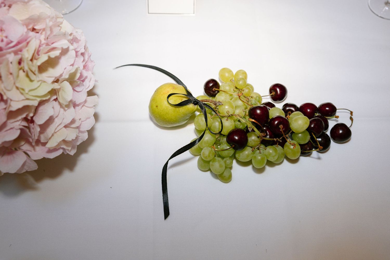 Fresh green grapes and dark cherries arranged on a white surface create an elegant fruit composition.