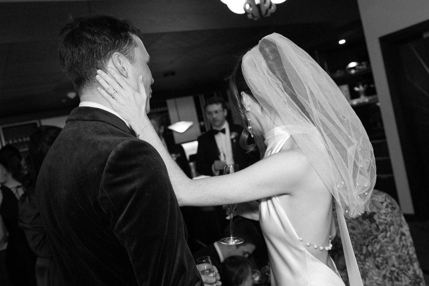 A tender moment between a bride and groom sharing a dance at their wedding reception captured in black and white.