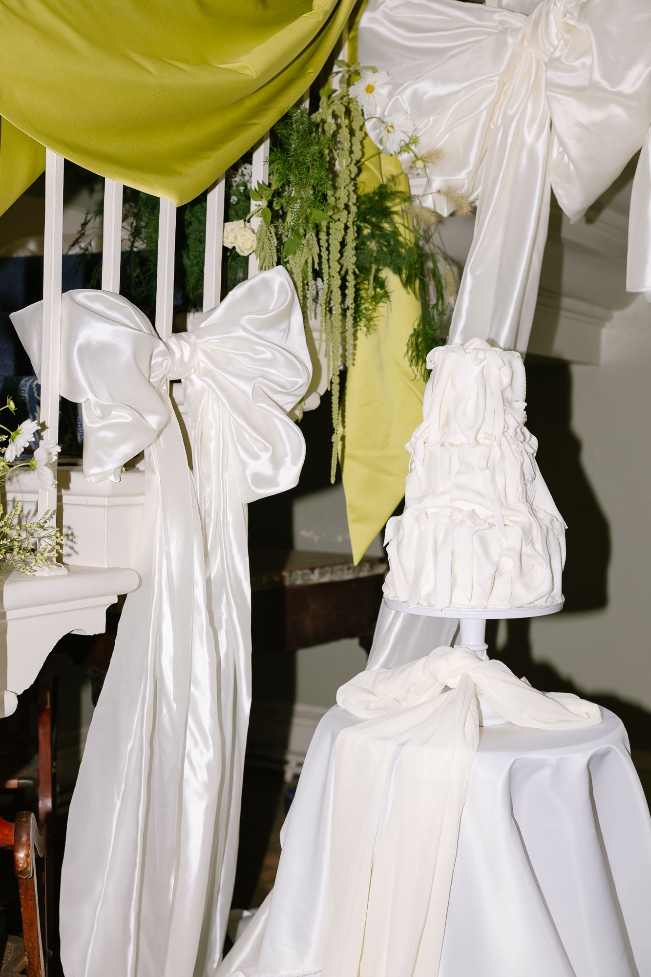 White fabric draped from green ceiling decorations creates an elegant wedding reception canopy arrangement.