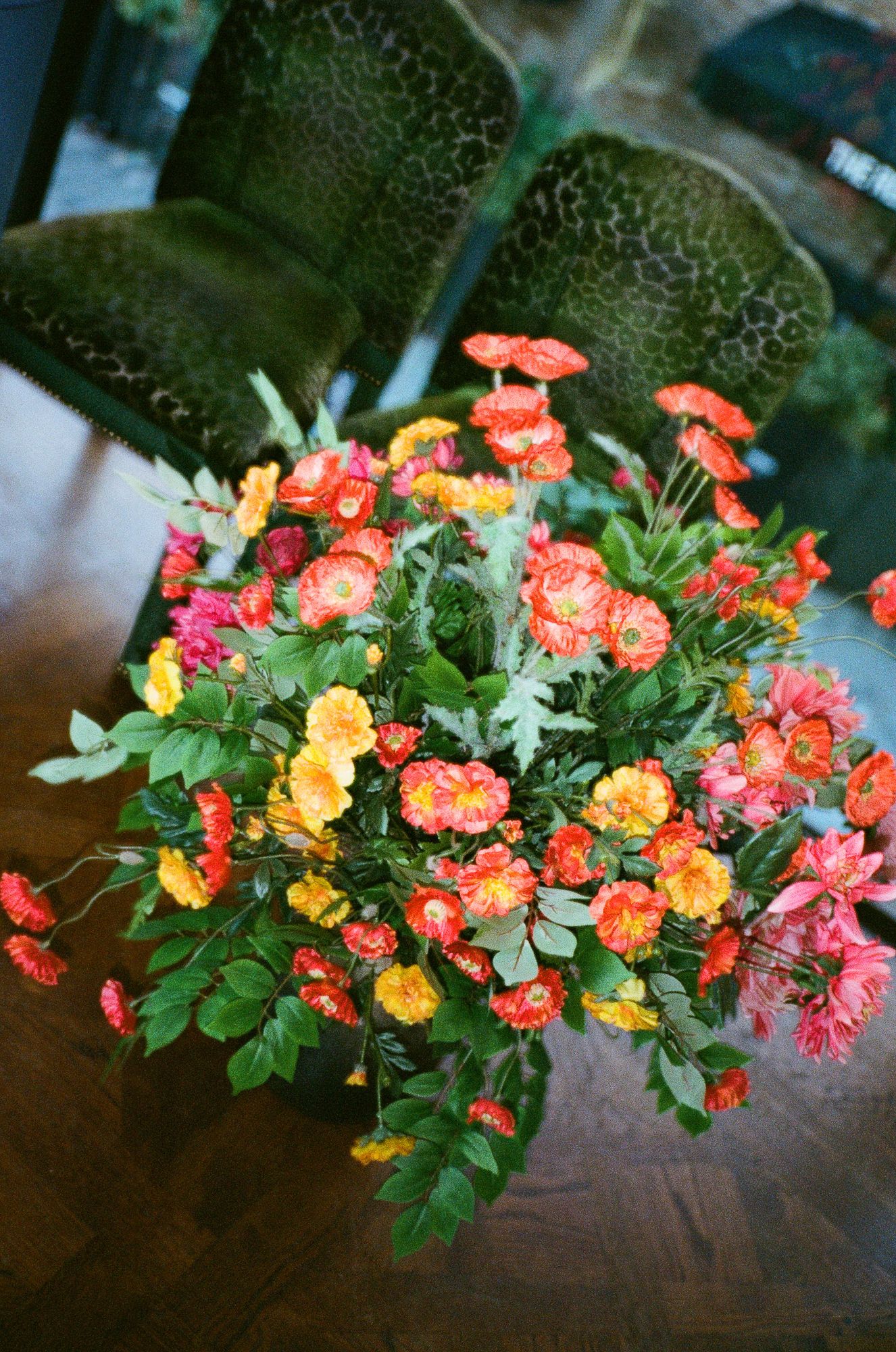 A collection of vibrant orange, yellow and pink roses arranged in a decorative display against a dark background.