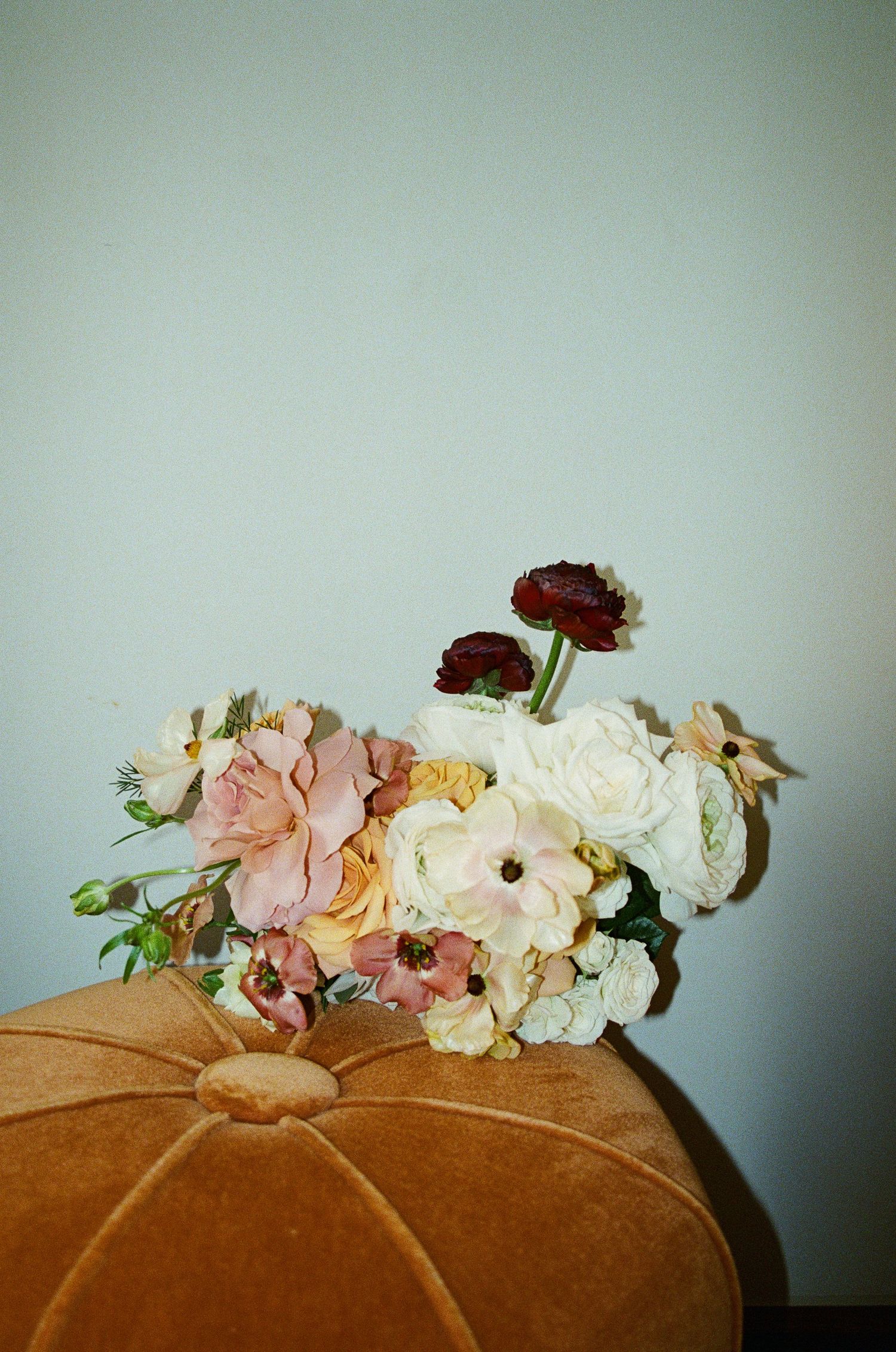 Floral arrangement with roses and mixed flowers on a velvet cushion.
