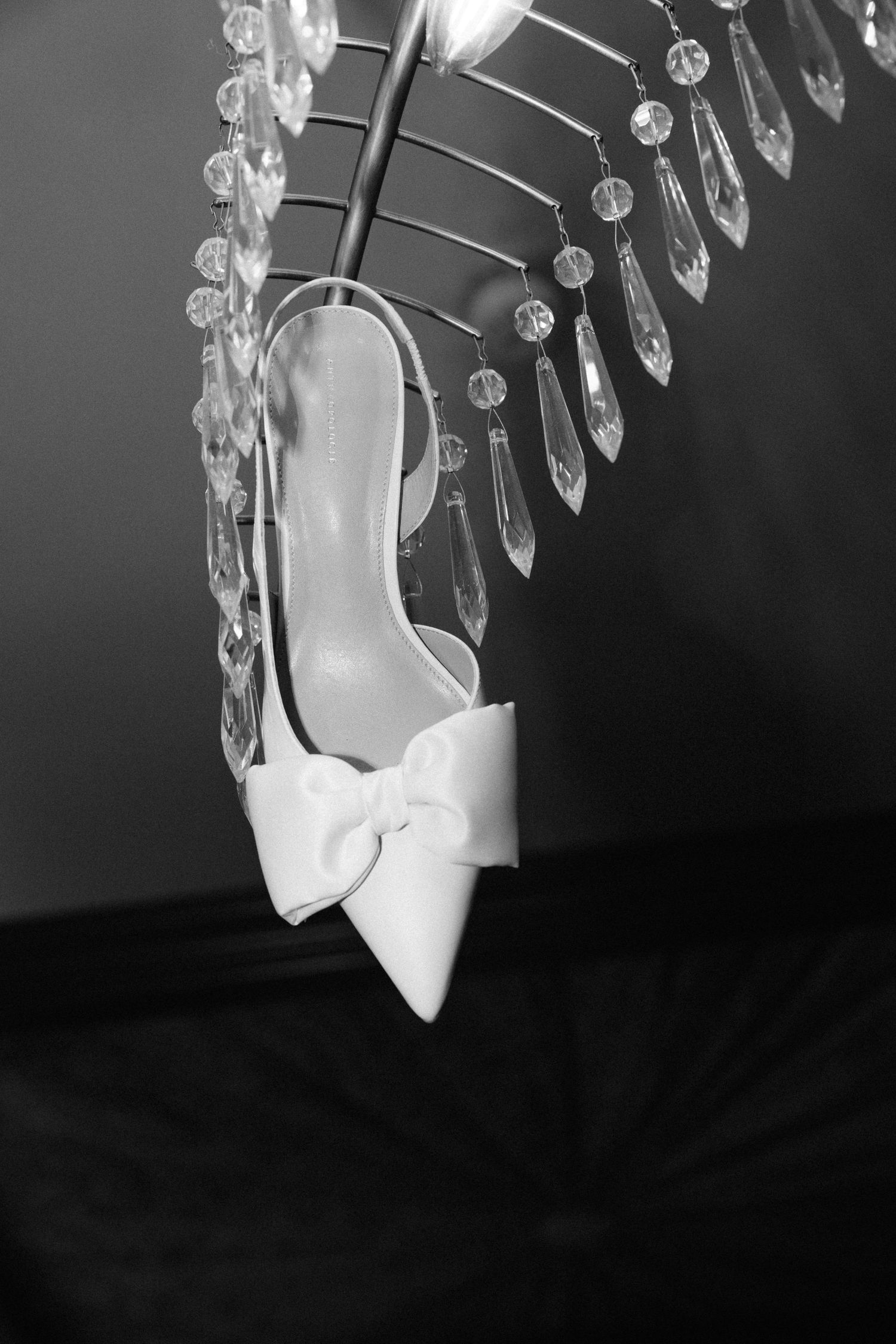 Crystal chandelier drops reflecting light against a dark background create a dramatic black and white composition.