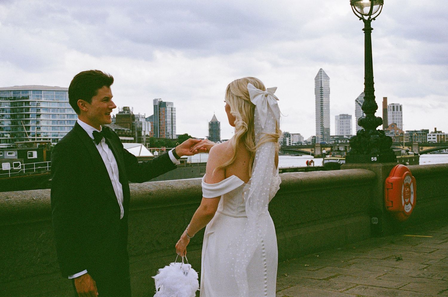 A wedding couple shares an intimate moment on a rooftop overlooking a city skyline during sunset.