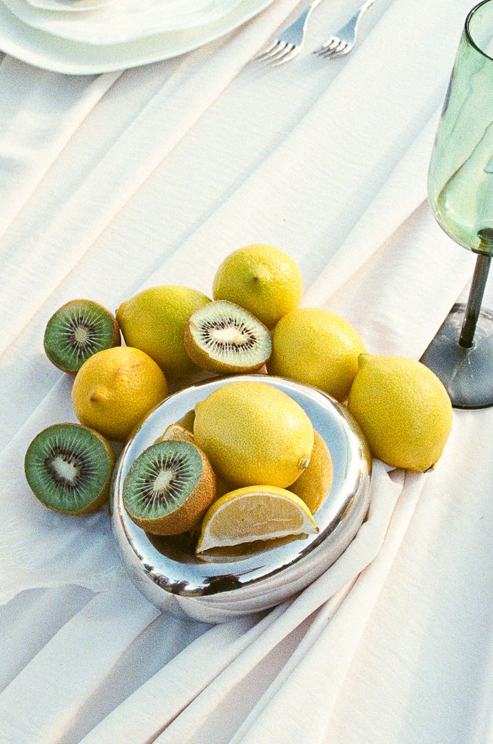 Fresh yellow lemons and sliced kiwi fruits arranged on white surface with soft natural lighting.