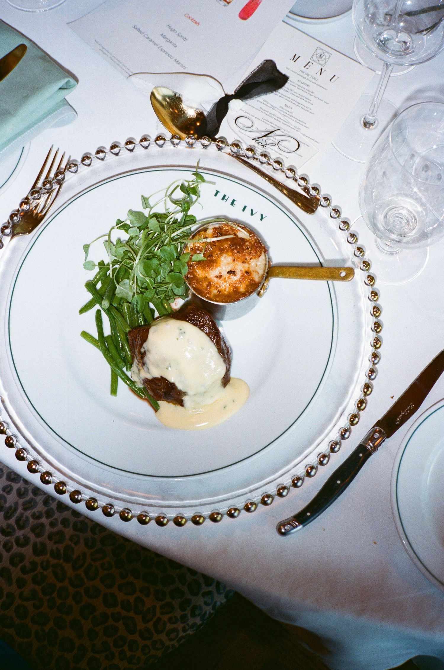 Elegant plated dish with white sauce and microgreens served on a decorative gold-rimmed plate at an upscale restaurant.