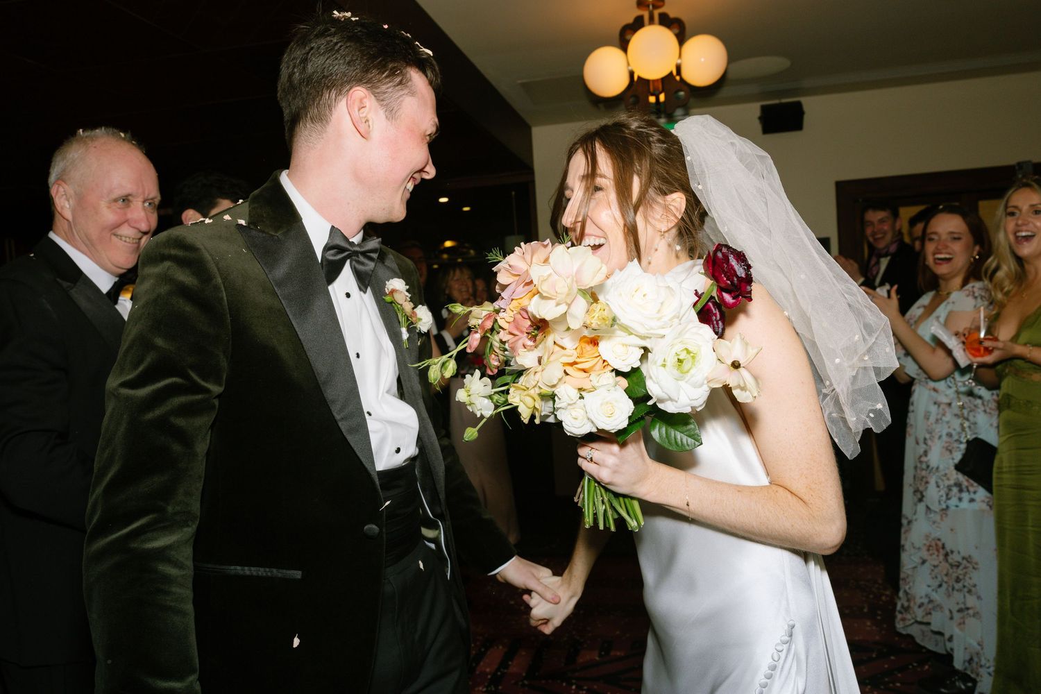 Happy couple sharing a moment during their wedding ceremony while holding a floral bouquet.