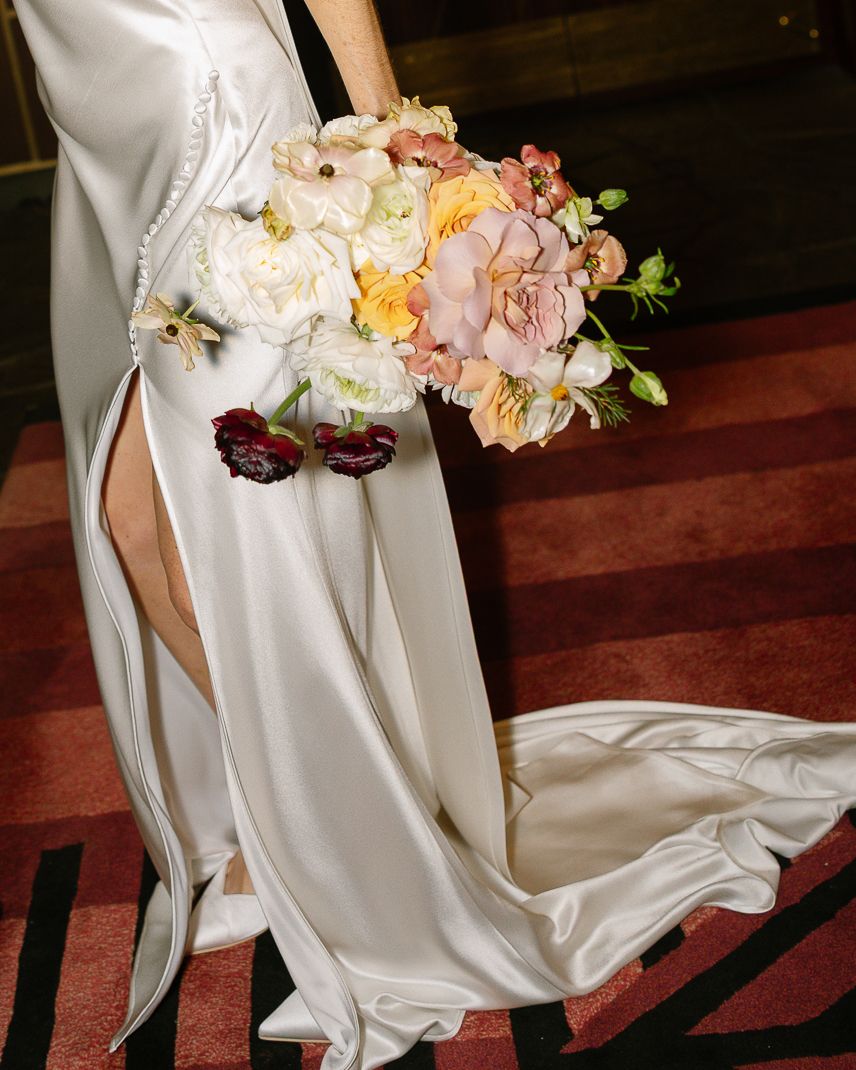 A series of white bridal dresses photographed from waist down, showing flowing skirts and bouquets on red carpet.