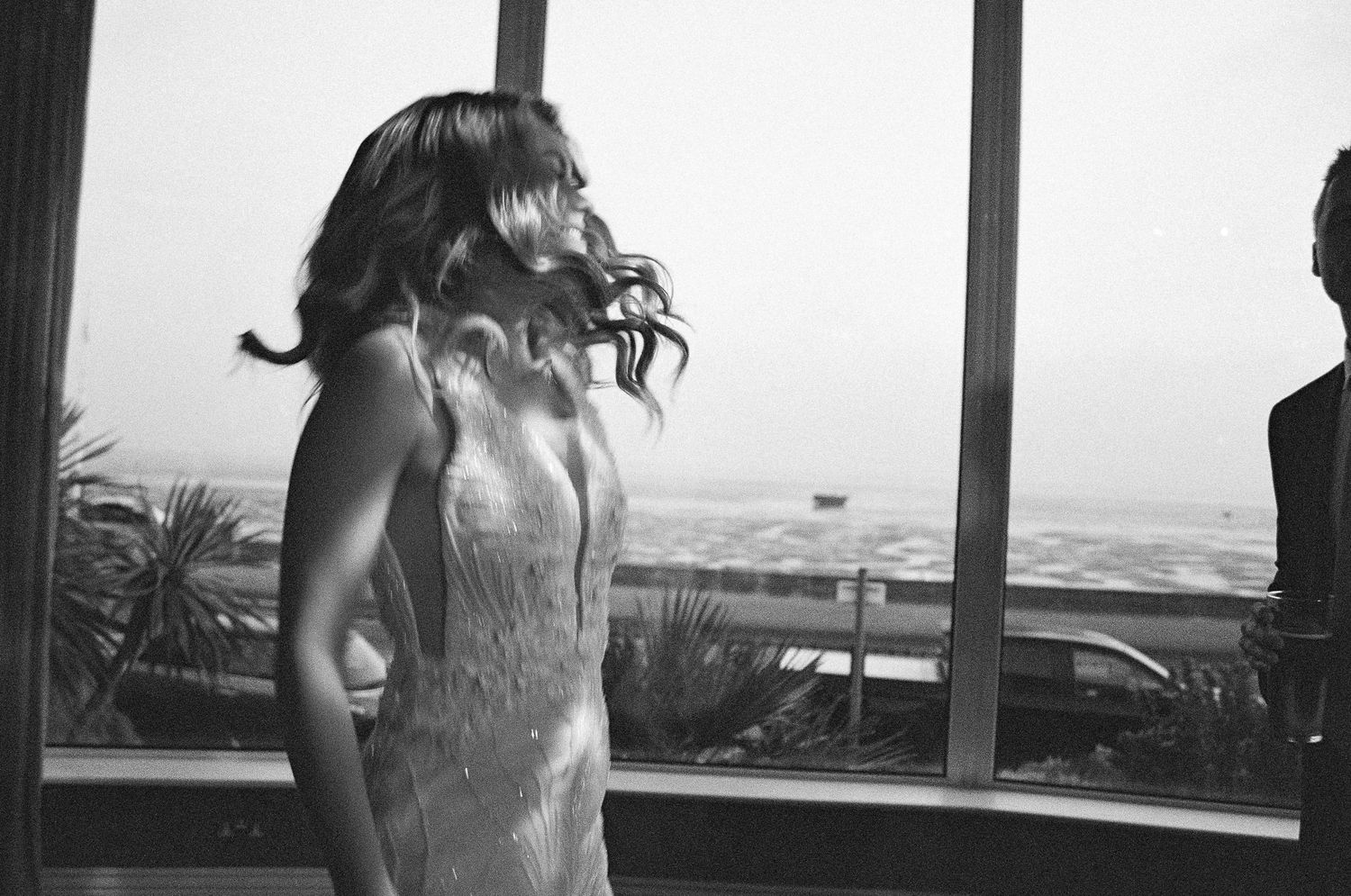 A black and white photograph showing a silhouette against large windows with an ocean view.