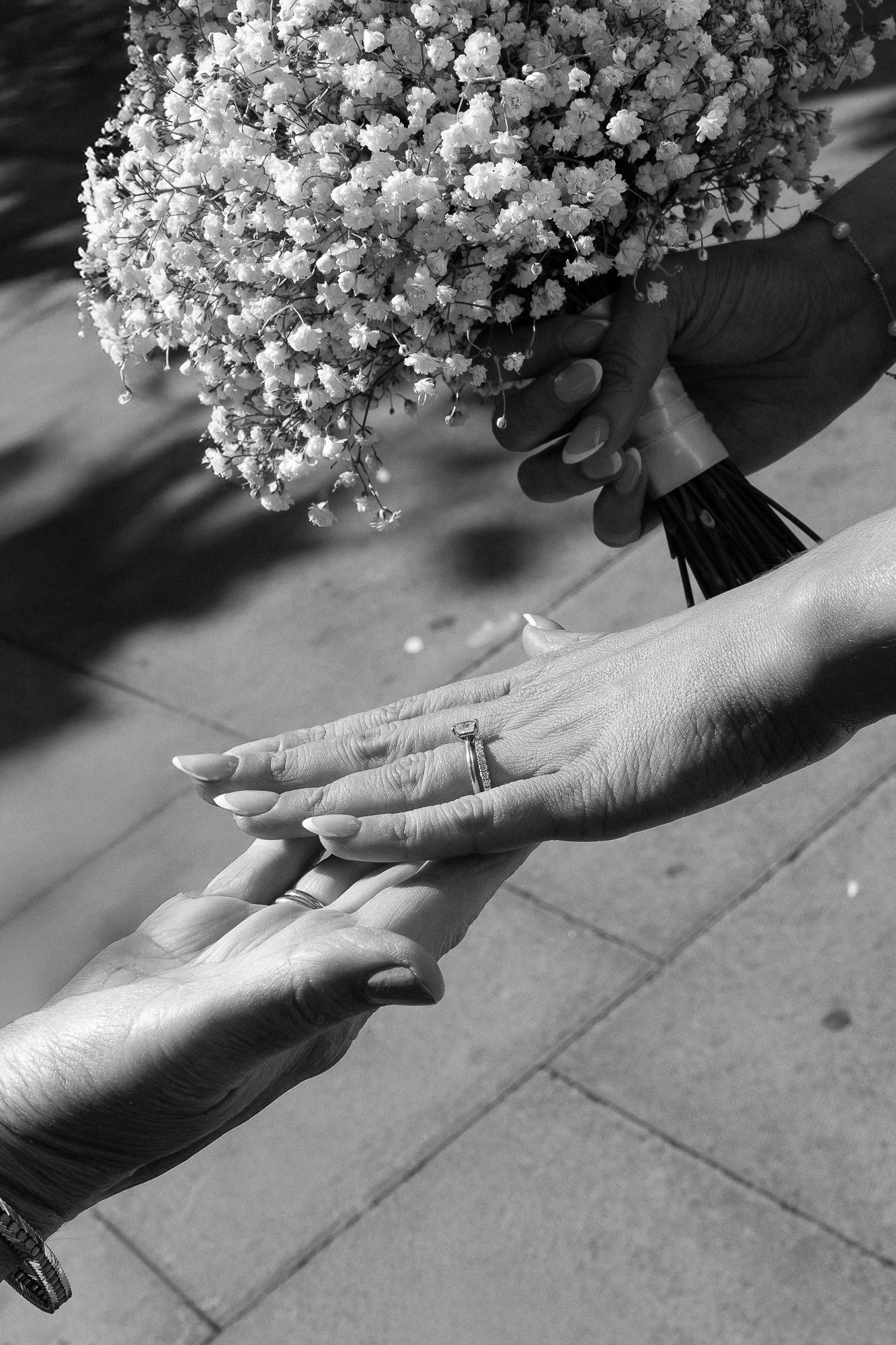 A black and white sequence of hands reaching towards a bouquet of baby's breath flowers against a light background.