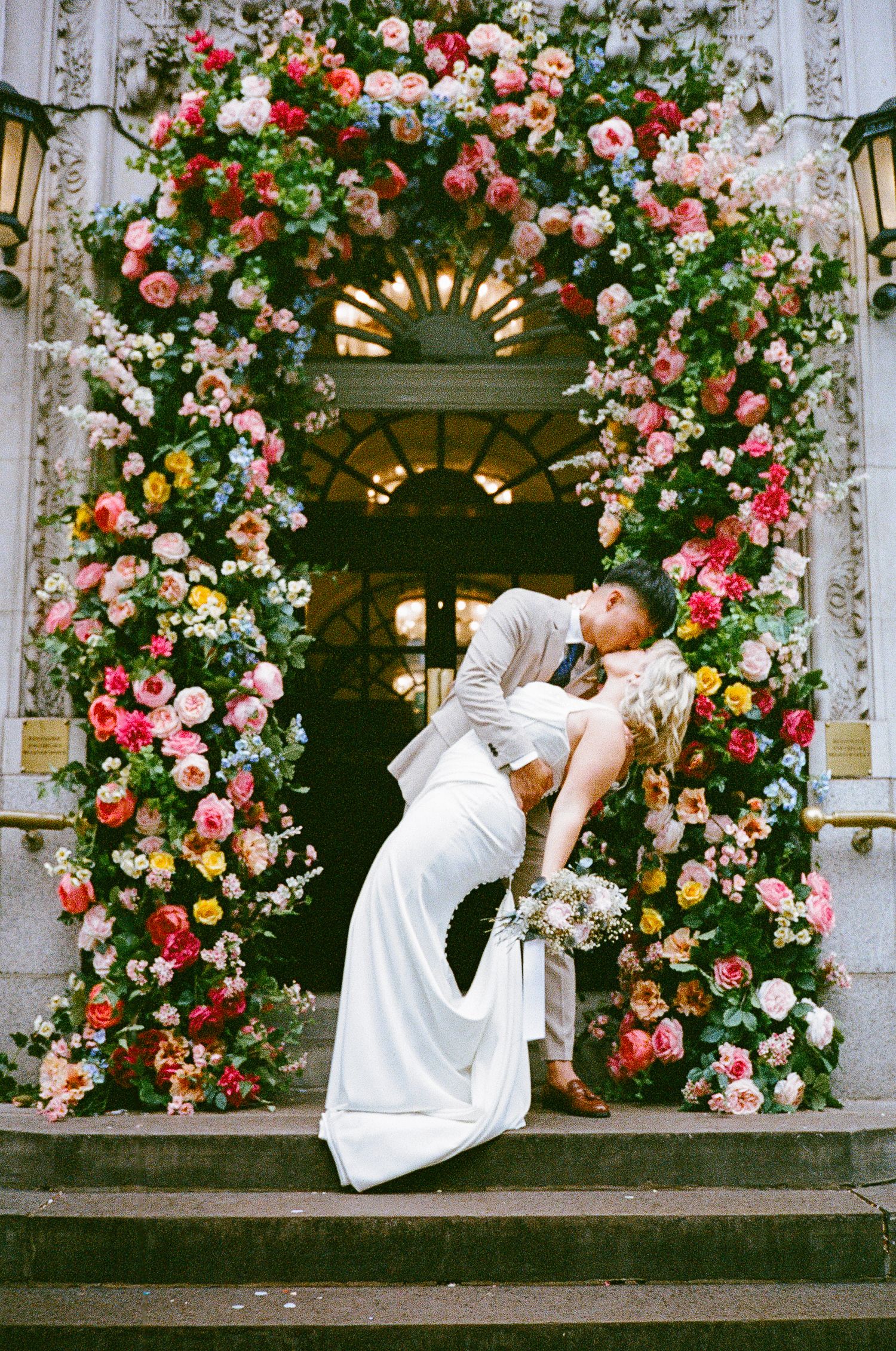 A series of romantic dance poses captured in front of an elegant floral arch with pink and peach roses.