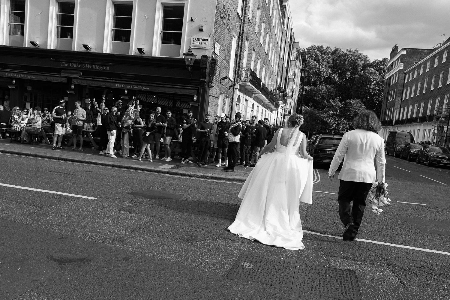 A black and white panoramic collage of street scenes showing people walking along city buildings and sidewalks.
