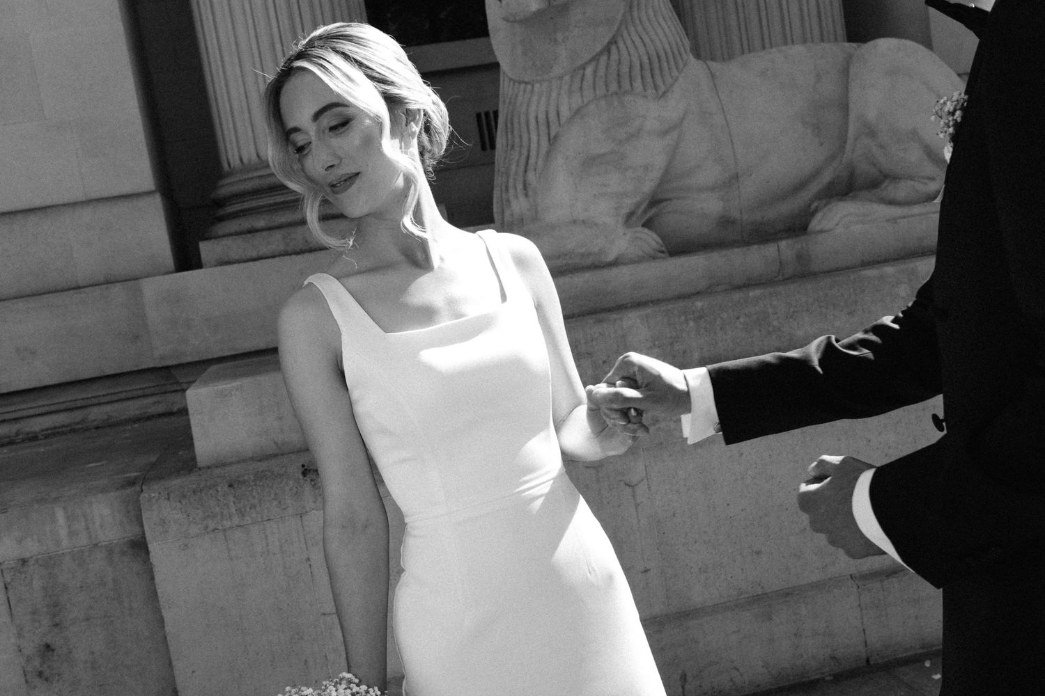 A bride in a white dress poses for photos in a series of black and white shots against a stone building exterior.