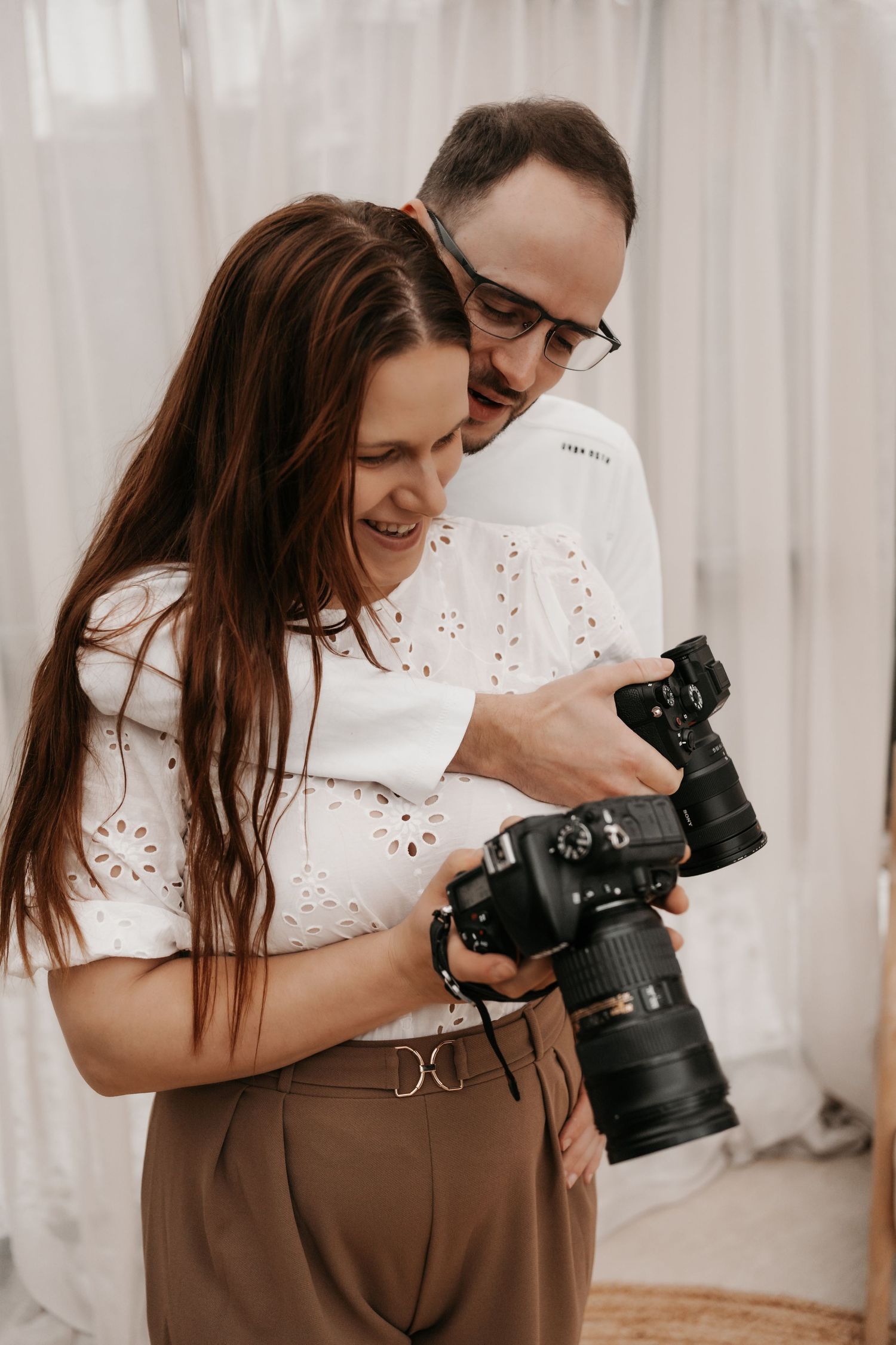 Professional photographers reviewing images together on camera display in bright studio setting.