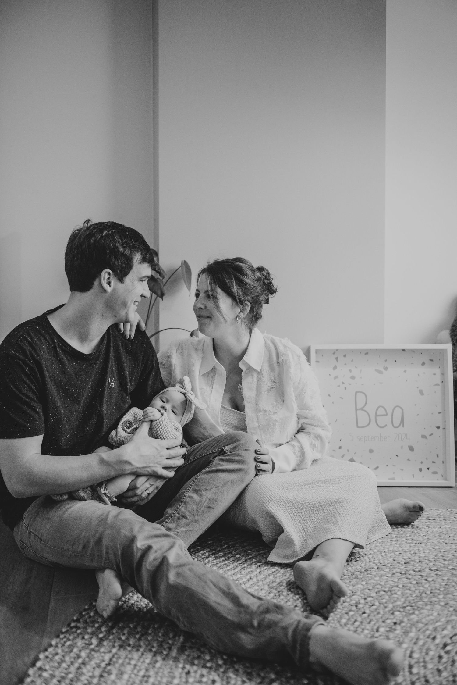 Family sharing intimate moments on patterned bedding in black and white.