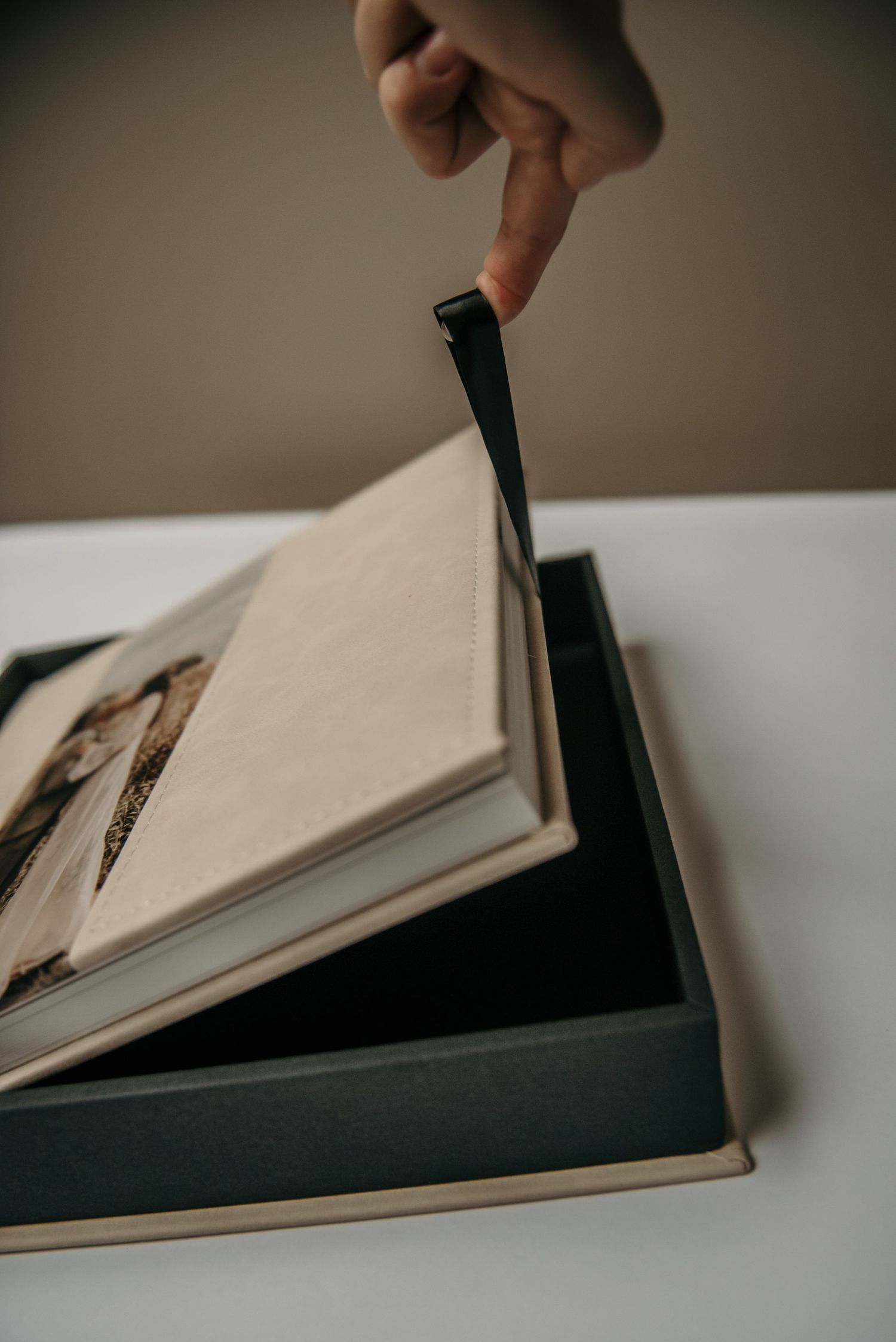 Hands carefully opening a black photo album containing vintage photographs.