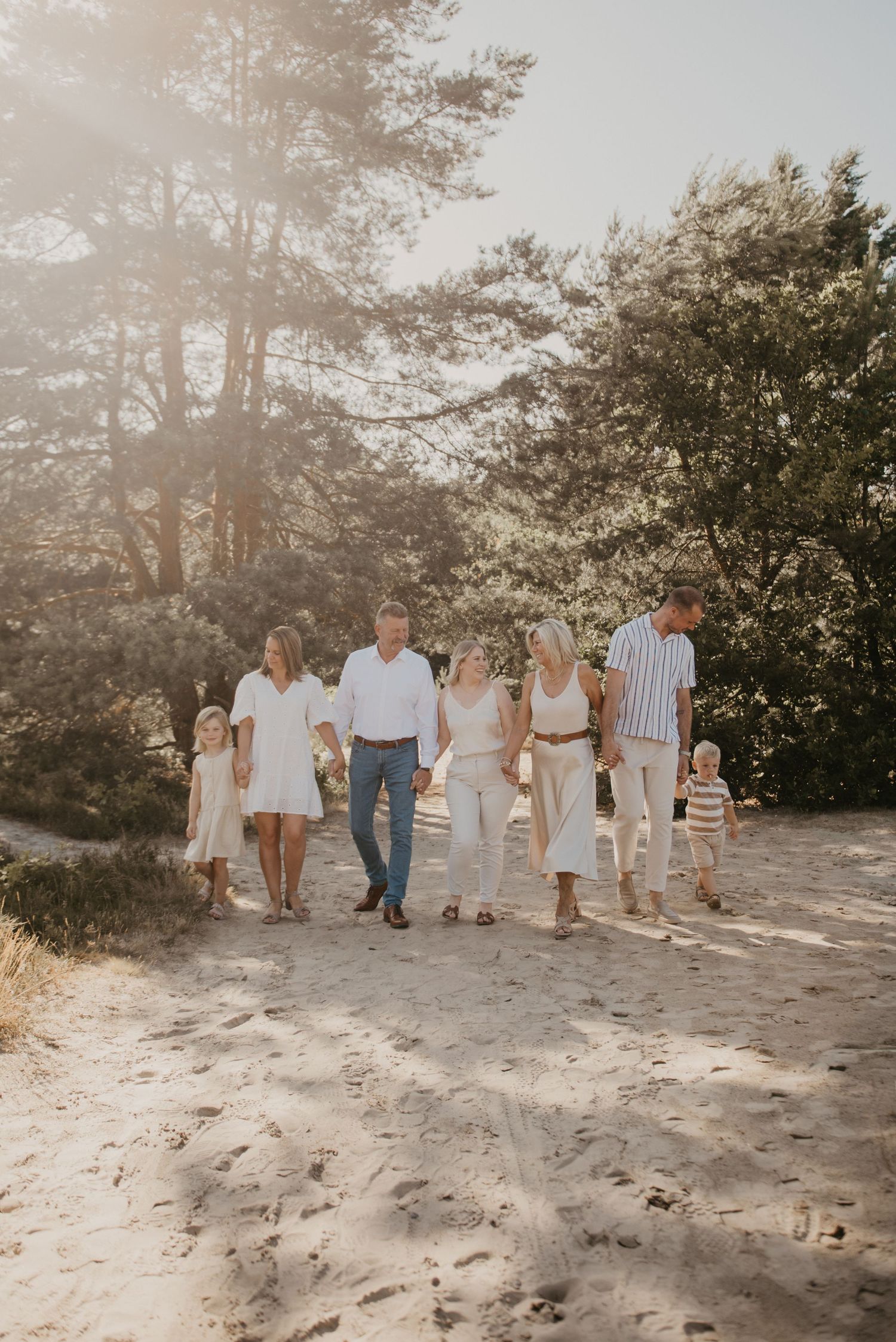 A group walks together along a sandy beach path during golden hour.