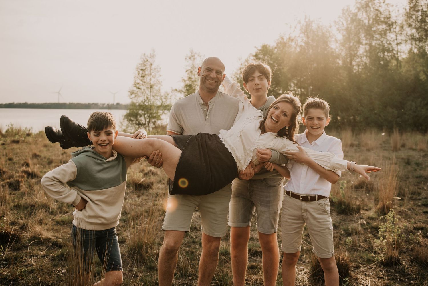 Family portrait at golden hour with everyone making silly poses outdoors.