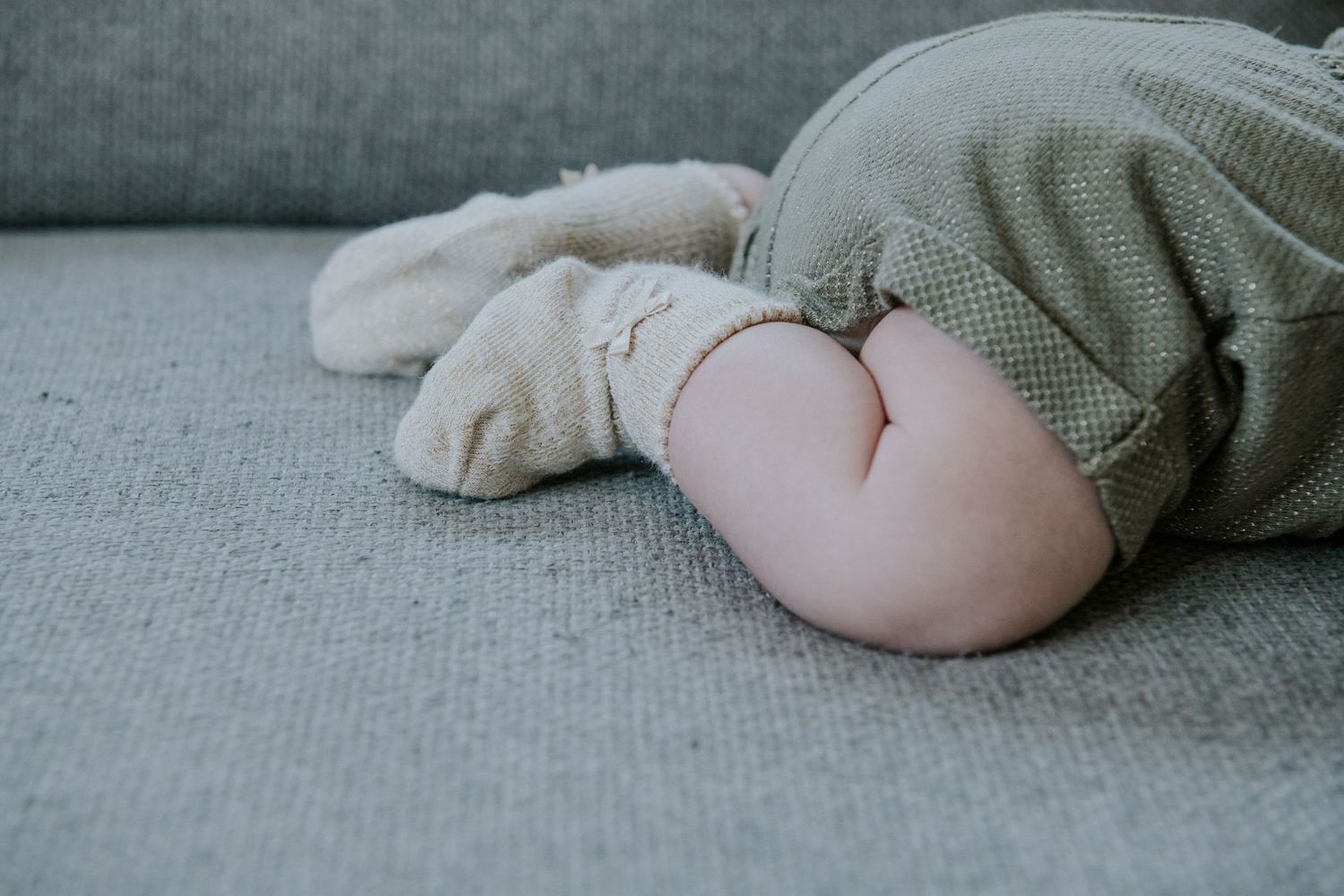 Close-up view of soft gray fabric texture with gentle folds and shadows.
