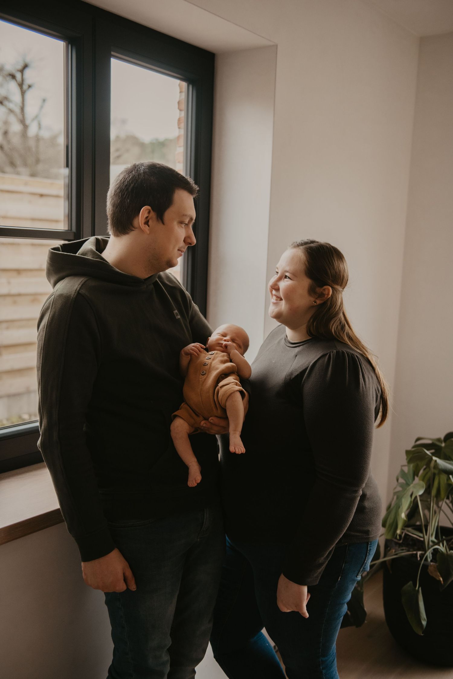 Family sharing joyful moment together near bright windows with indoor plant.