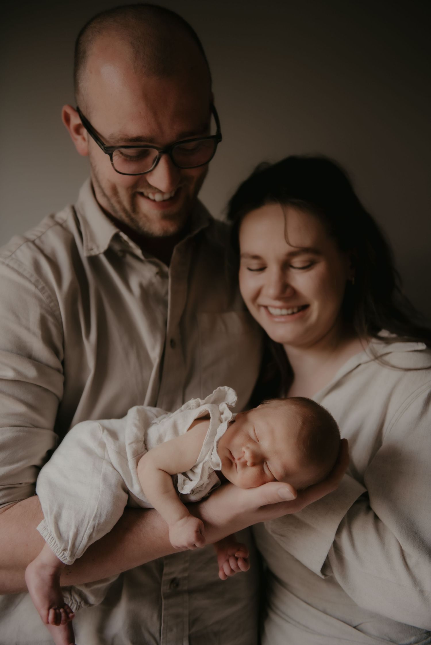 Tender family moment with a newborn baby being cradled in a moody setting.