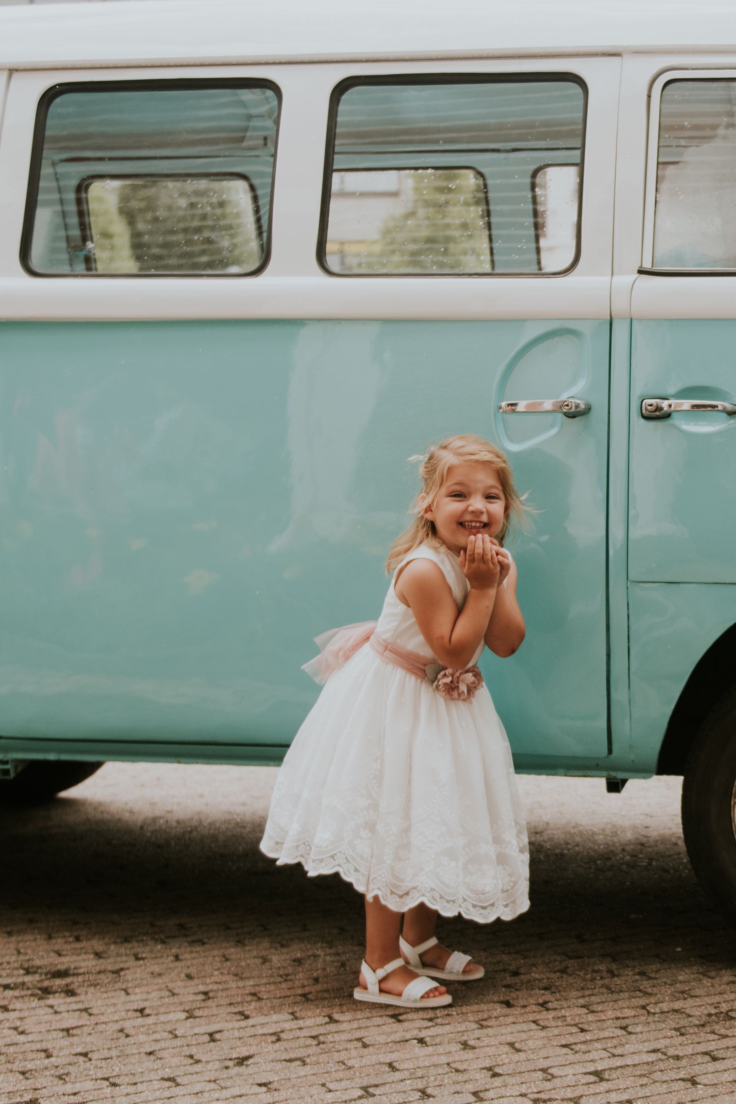 Playful moments captured near vintage mint green VW van at wedding.